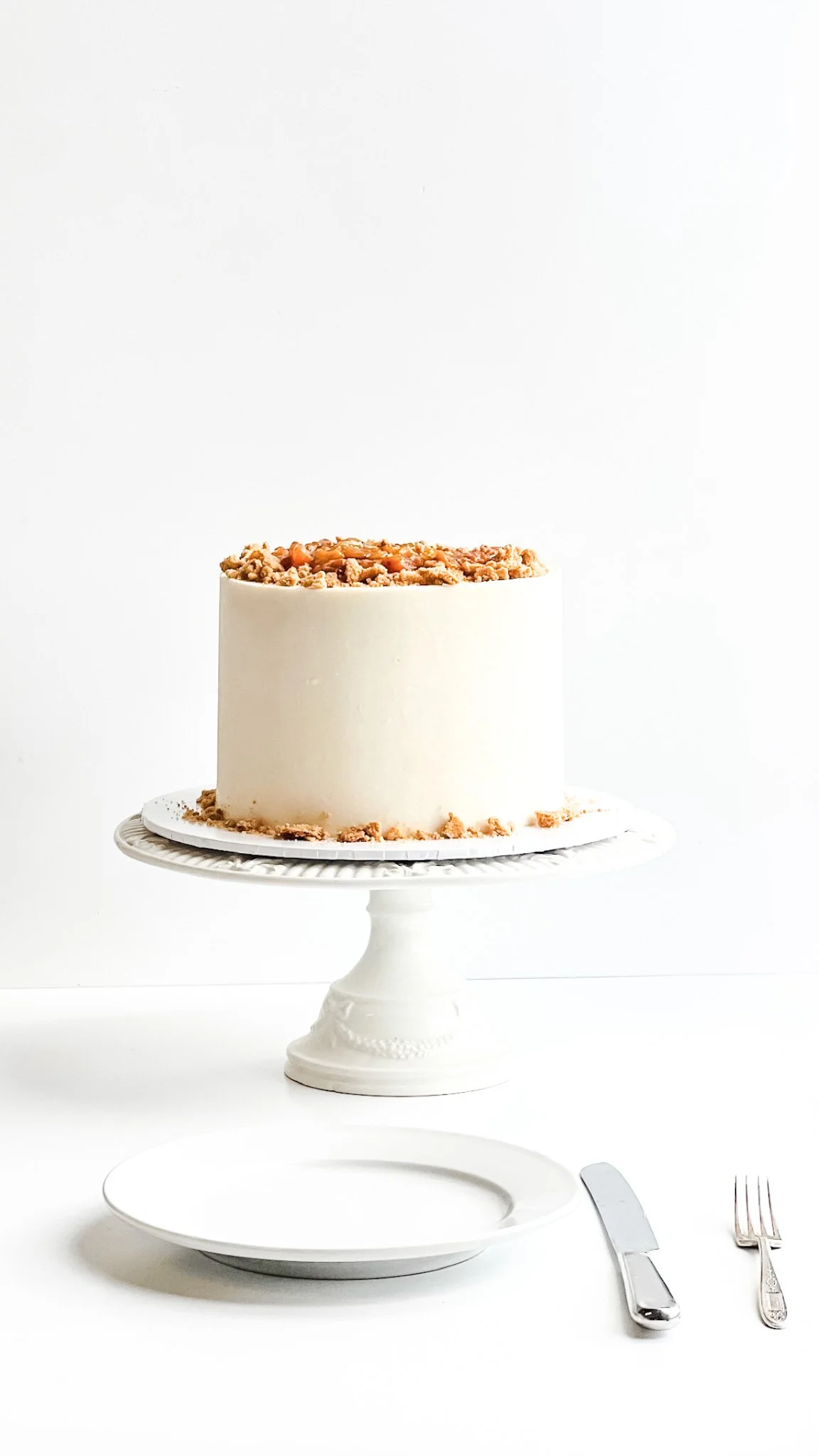 Peach Cobbler Cake sitting on a white cake stand against a white background