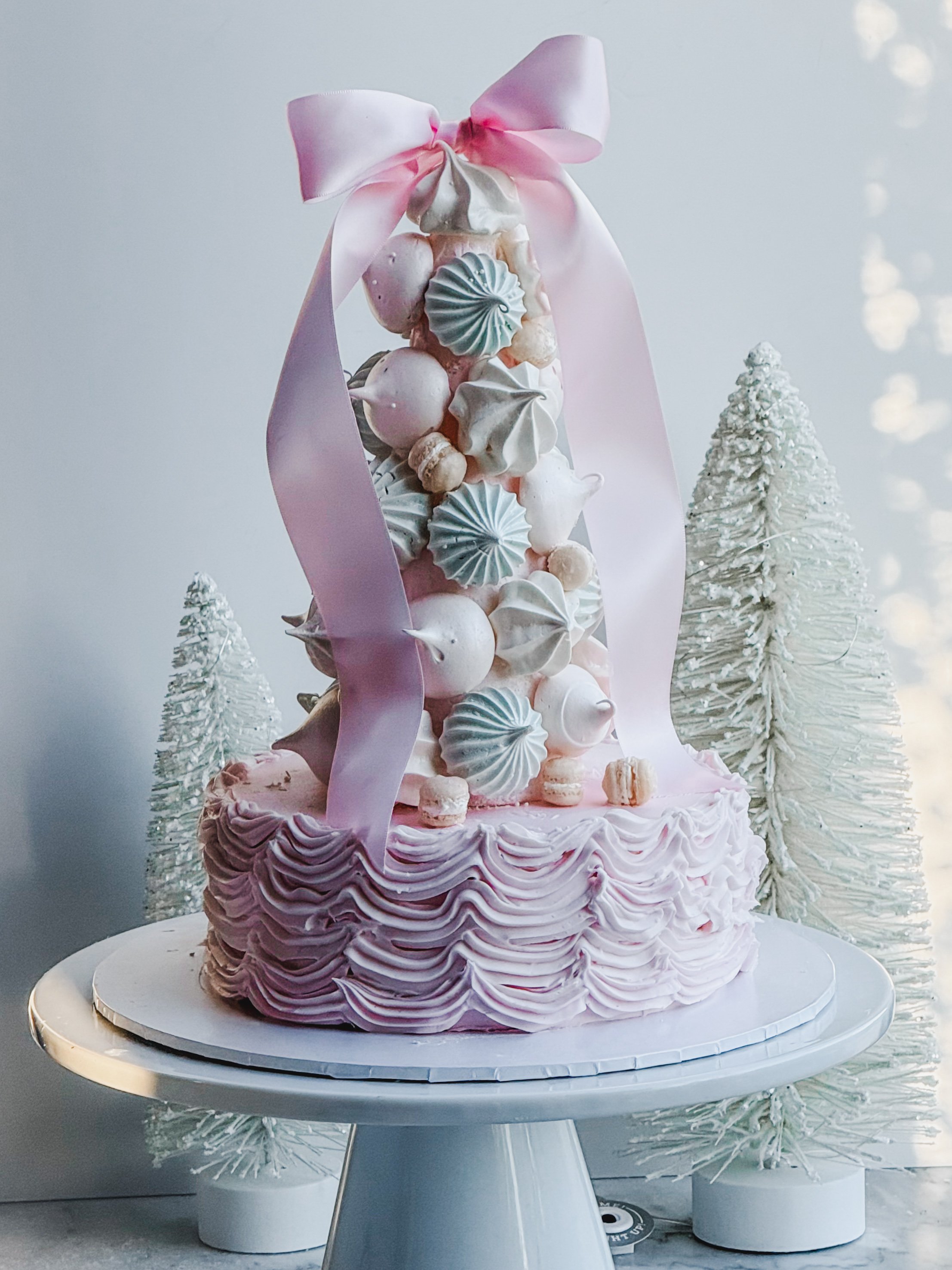 Pavlova Tree made of pastel pavlovas stacked to resemble a Christmas tree adorned with a pink ribbon