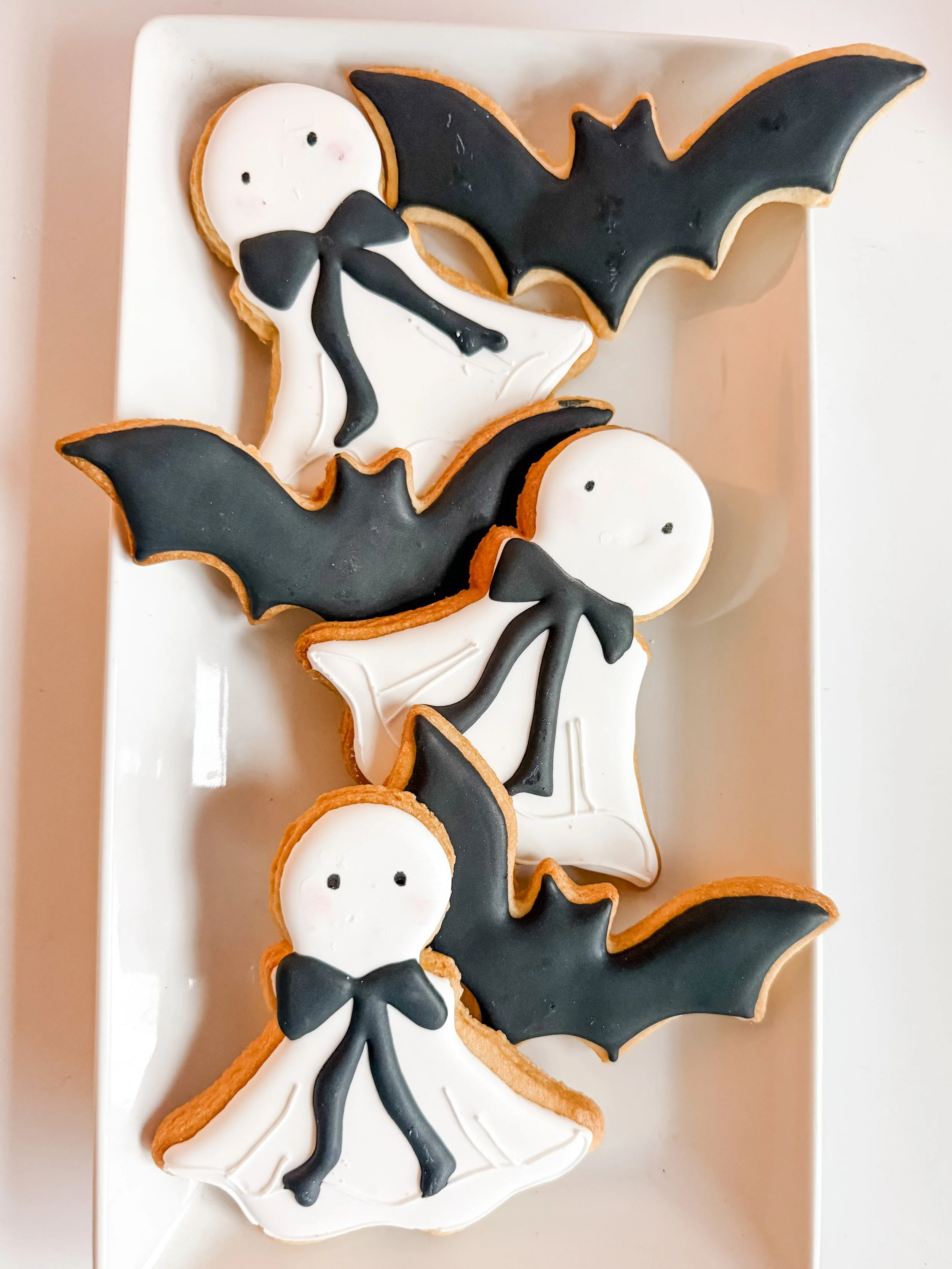 halloween decorated sugar cookies in the shapes of bats and ghosts