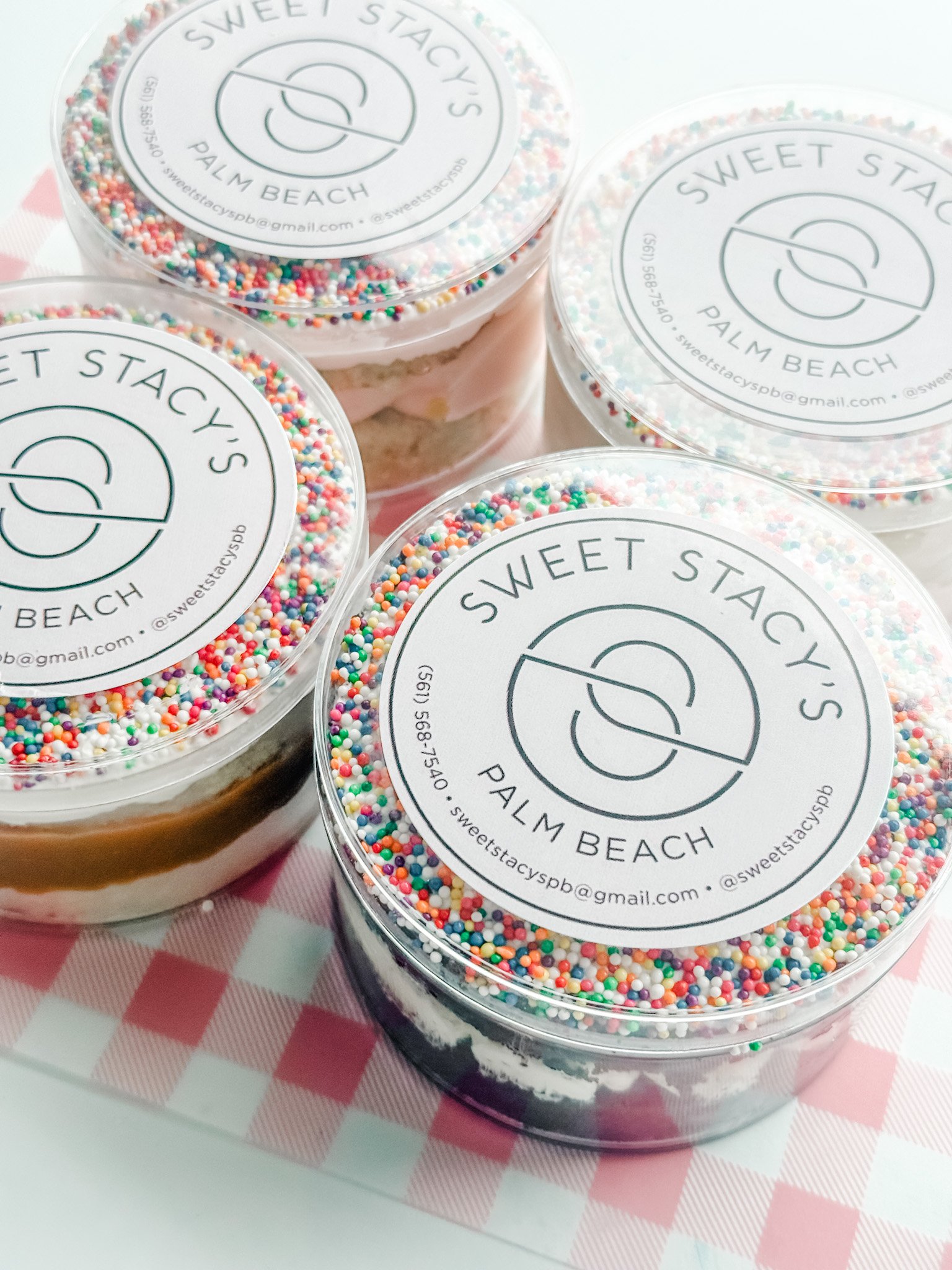 individually packaged vanilla and chocolate dot cakes in clear containers with the sweet Stacys logo with frosting and rainbow sprinkles
