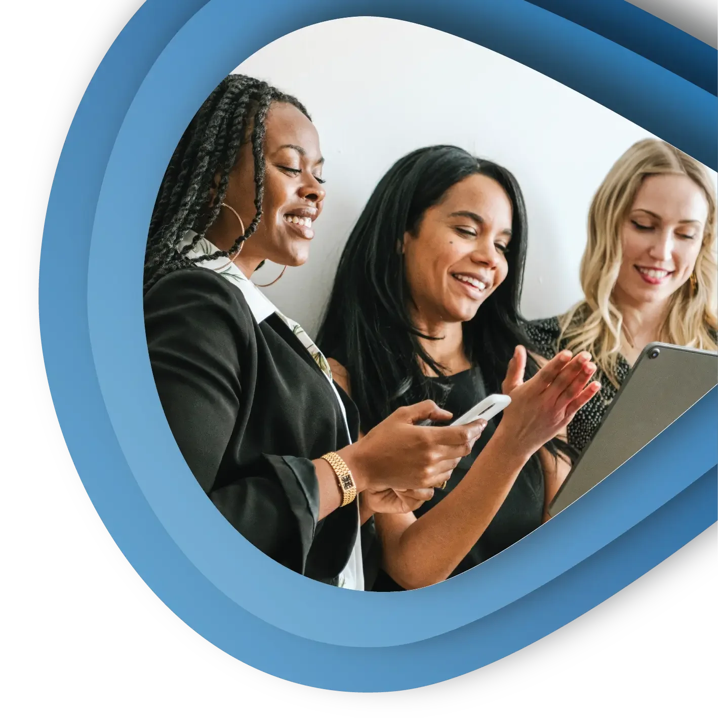 Three professional women stand in a line looking at devices and talking