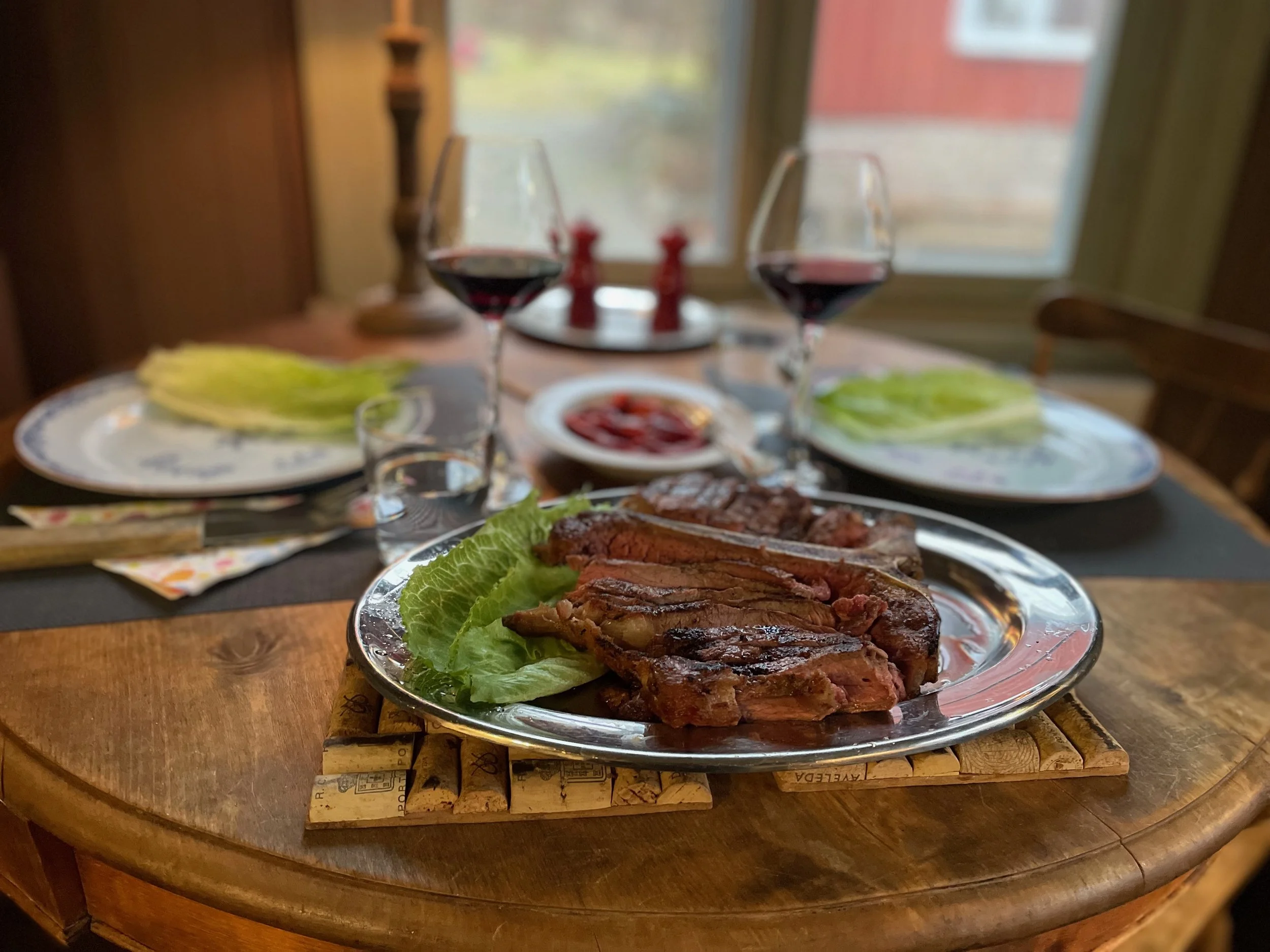 A dinner table set with wine, steak, lettuce, and condiments.