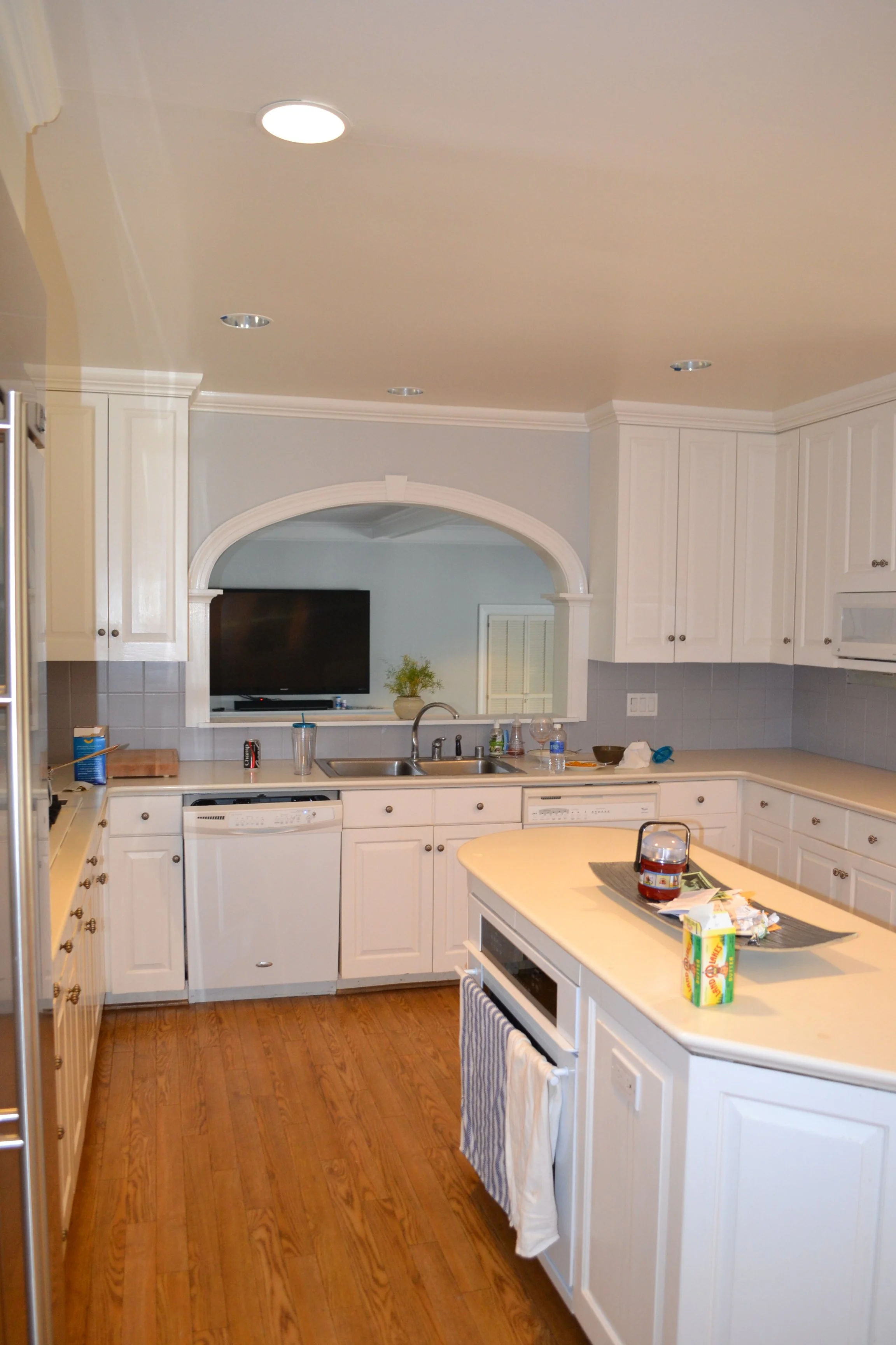 A cramped, traditional kitchen layout with a disruptive arched pass-through wall before an open-concept architectural renovation.