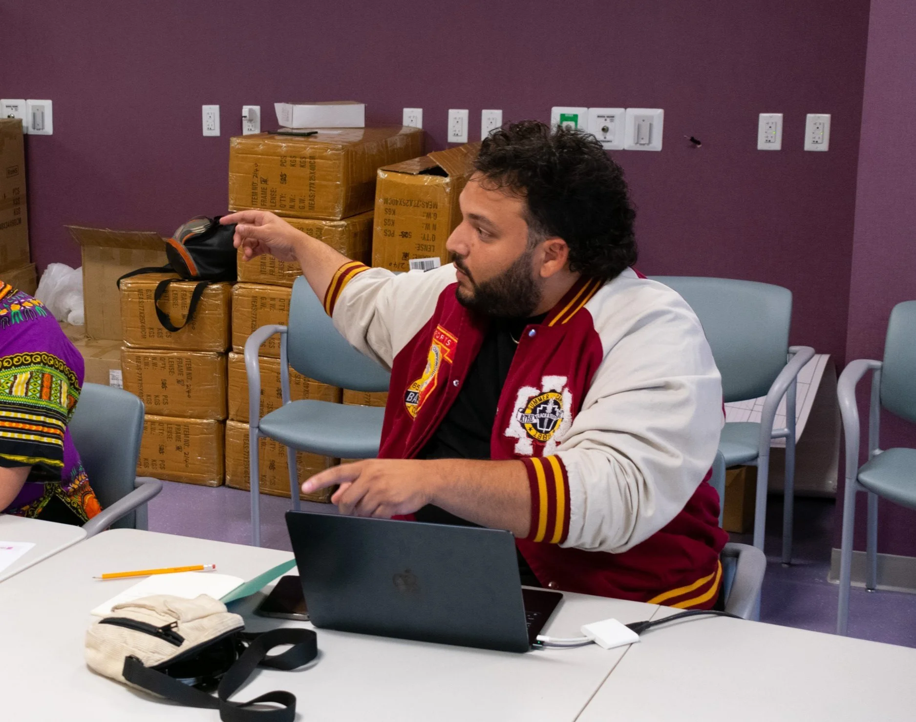 A bearded man sitting at a table with laptops in front of them.
