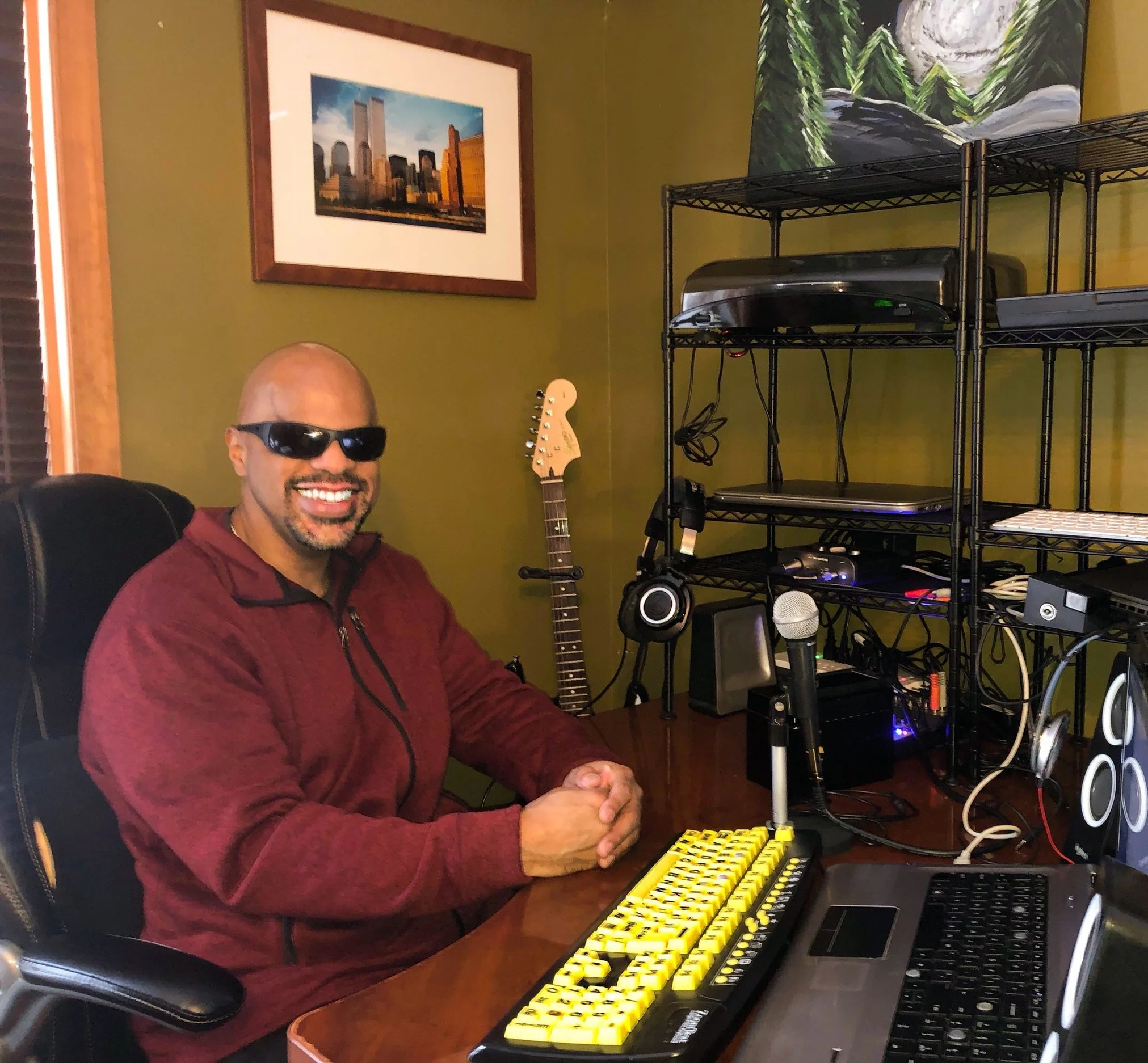 A man smiling beside their recording studio setup.