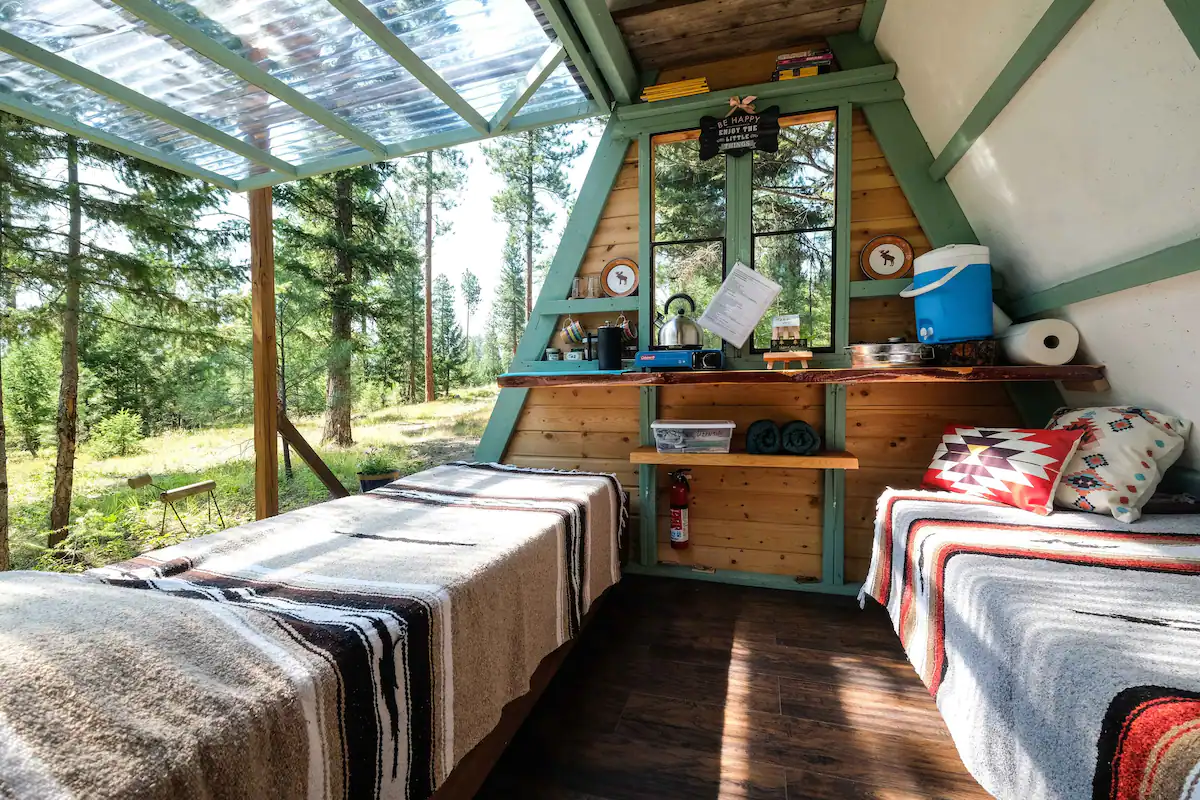Interior of the Transforming Forest Cabin showing the rope-operated wall open to 360-degree Montana forest views.