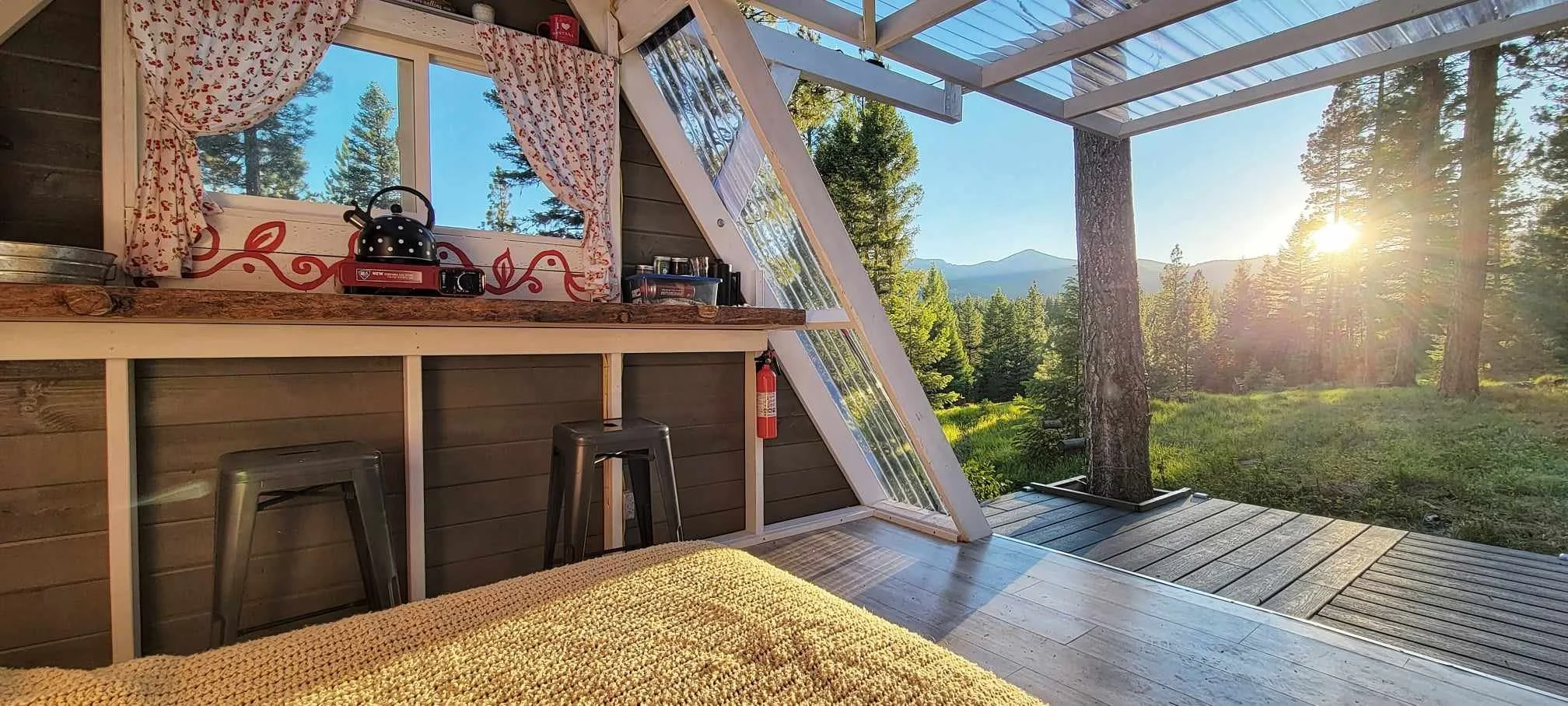 Interior view of The Stargazer cabin showing the queen bed and open wall for stargazing on 100 private acres.