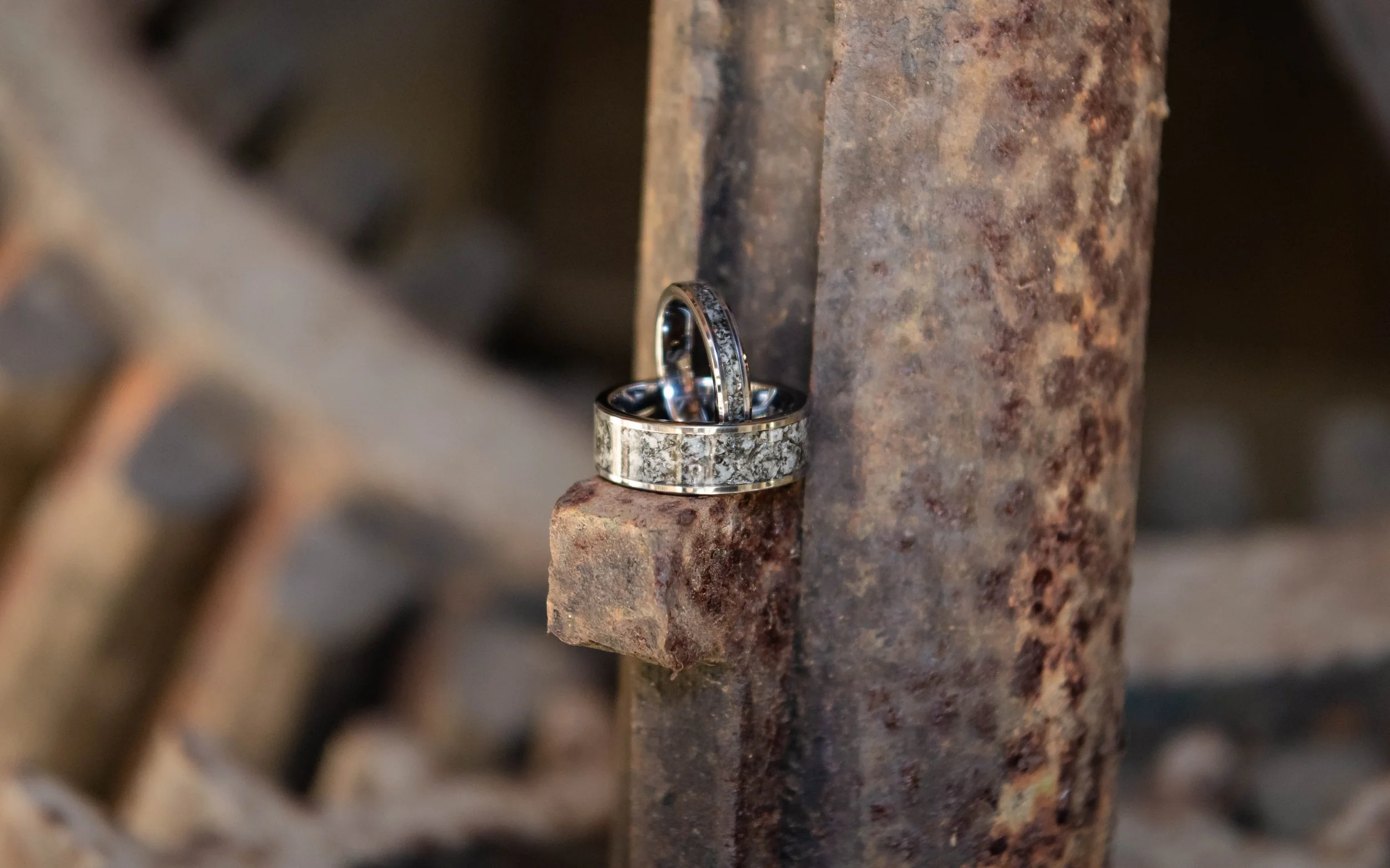 Two silver wedding rings resting on a rusted metal surface.