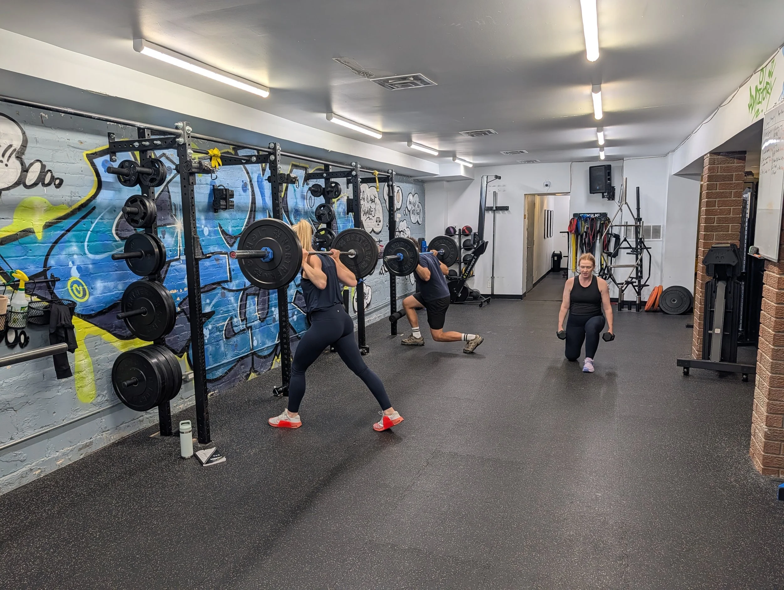 A small group training class with personal trainer coaching form during work session.