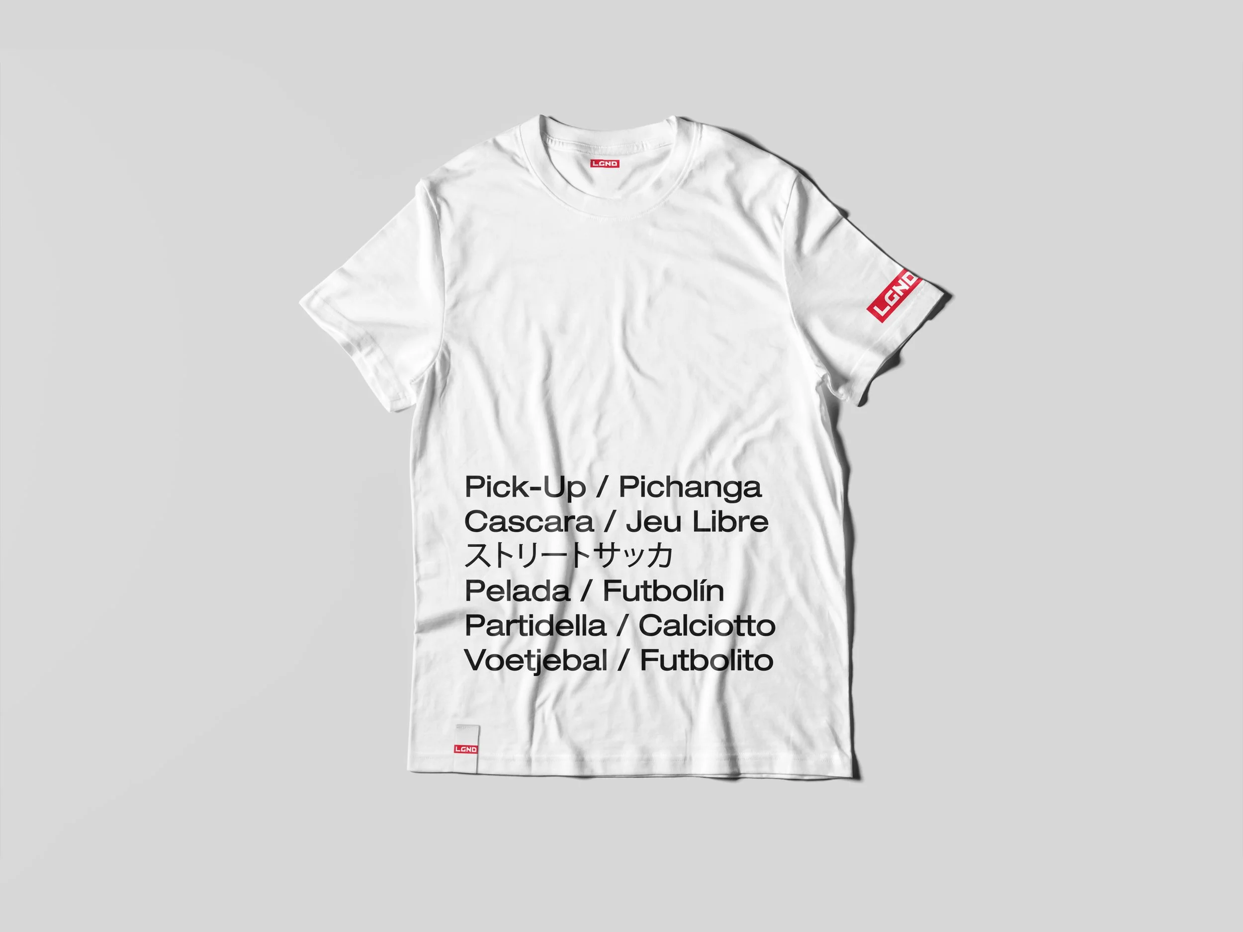 White T-shirt lying flat on a gray background with text and red logo on the front.