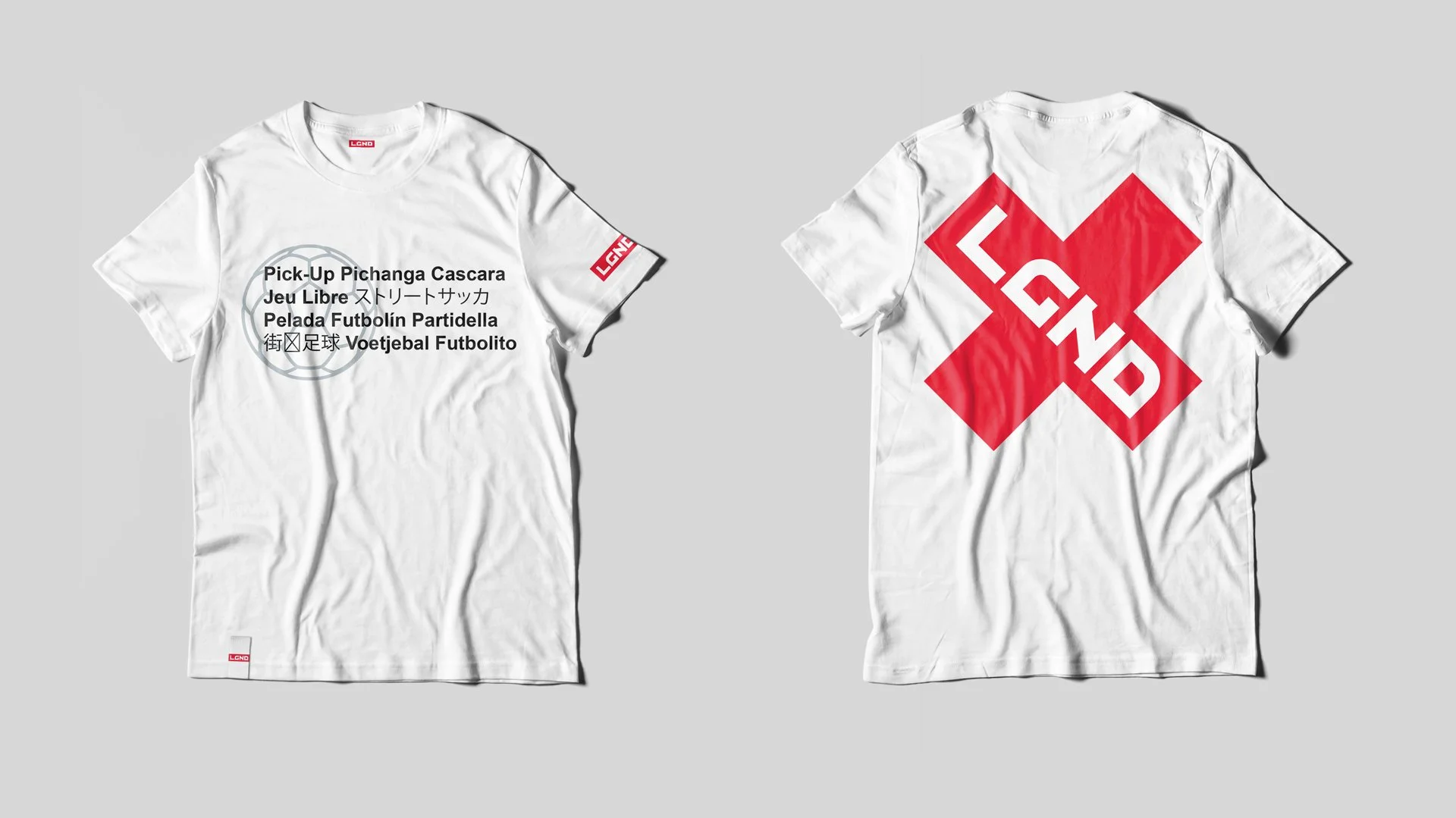 Two white T-shirts laid flat on a gray background. The front shirt has black and Japanese text, a circle graphic, and red labels on the sleeves and bottom corner. The back shirt features a large red geometric logo with the letters LCND diagonally acr