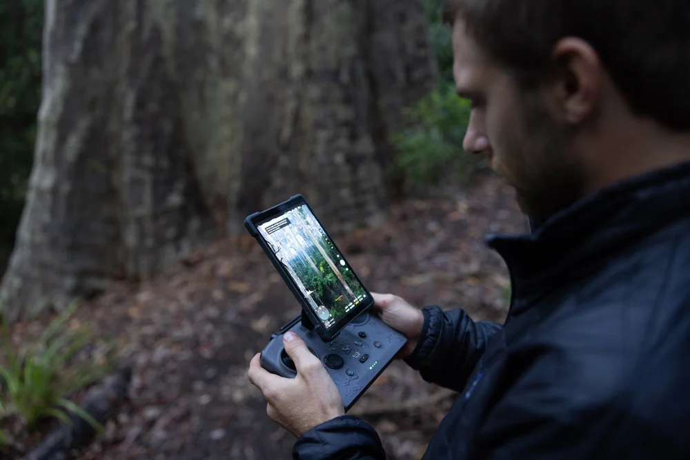 Andrew Kaineder operating a drone while filming in the forest.