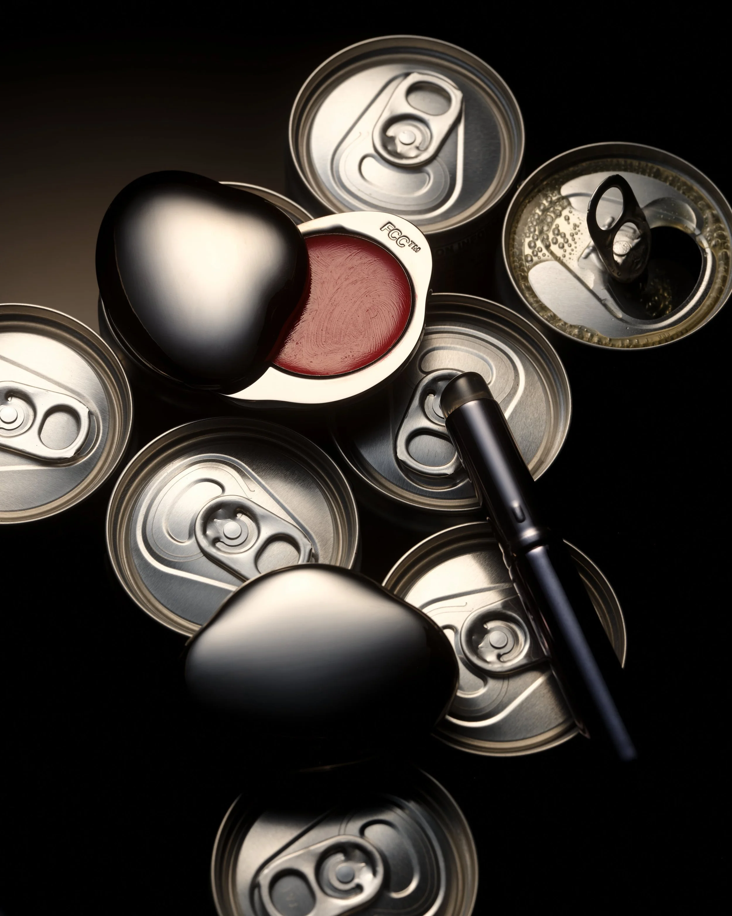 An overhead view of multiple aluminum cans and a black and silver pull tab.