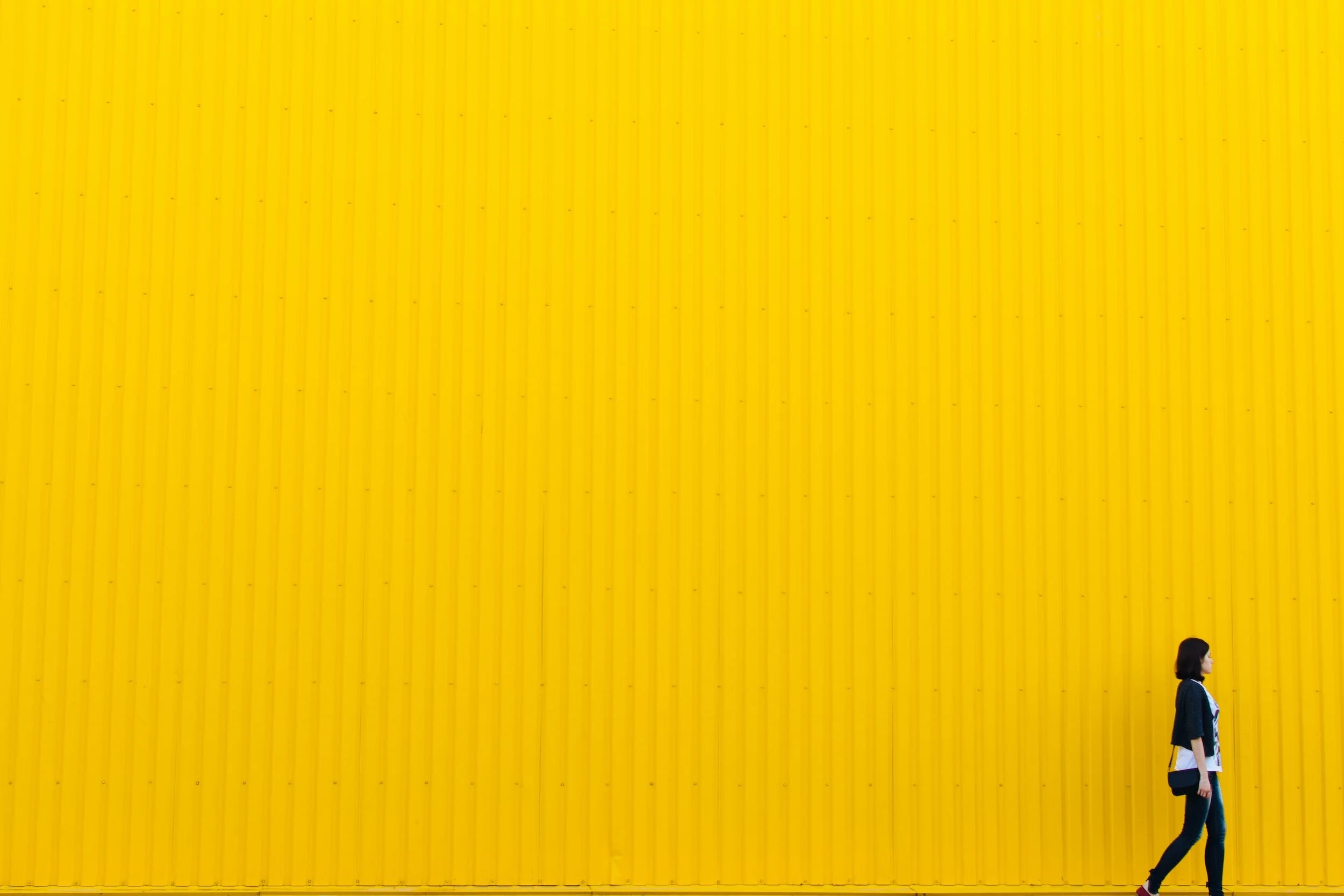 Woman walkingin front of a bright yellow background