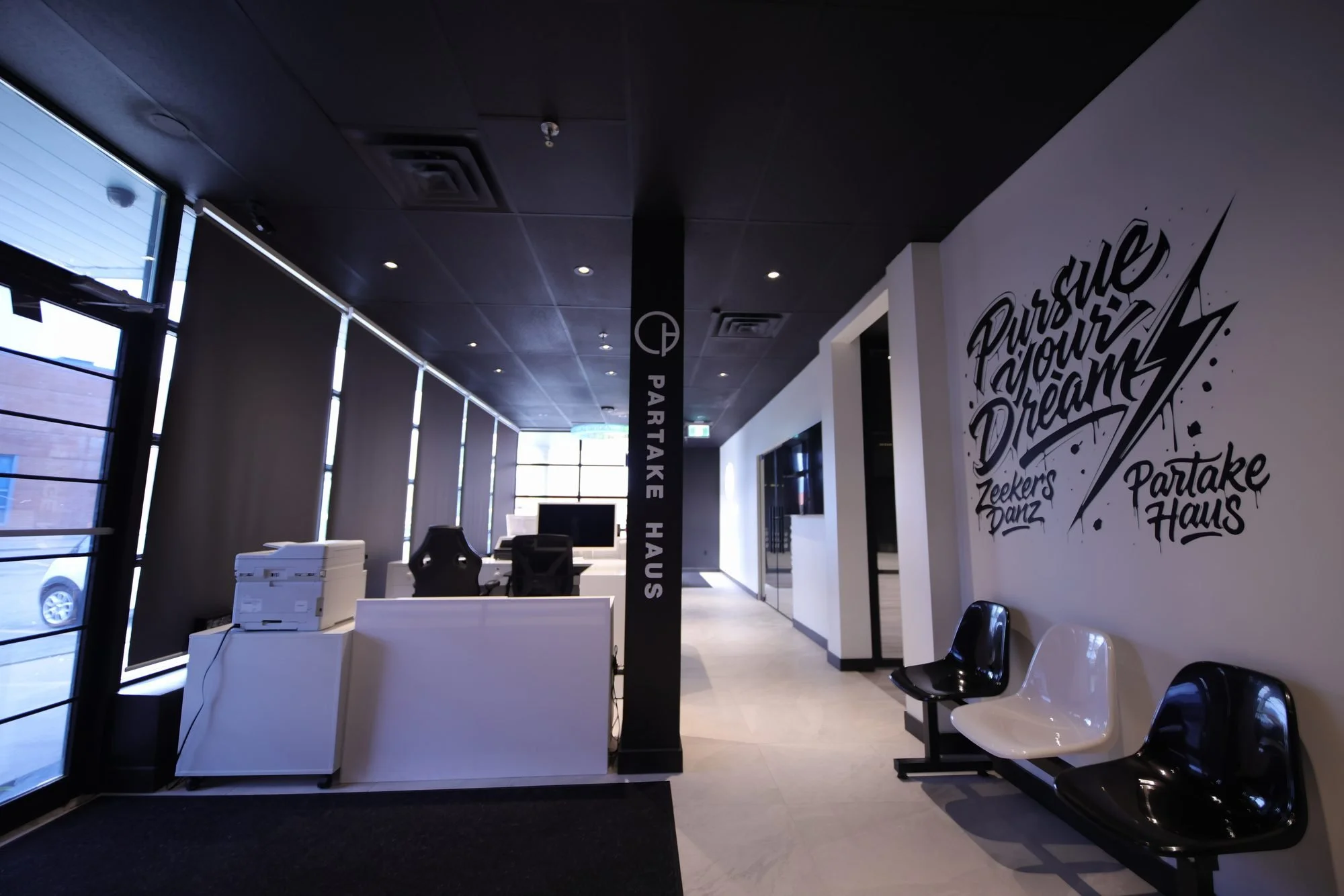 The ZeekersDanz front desk and waiting chairs, with the Pursue Your Dream mural on the wall behind.