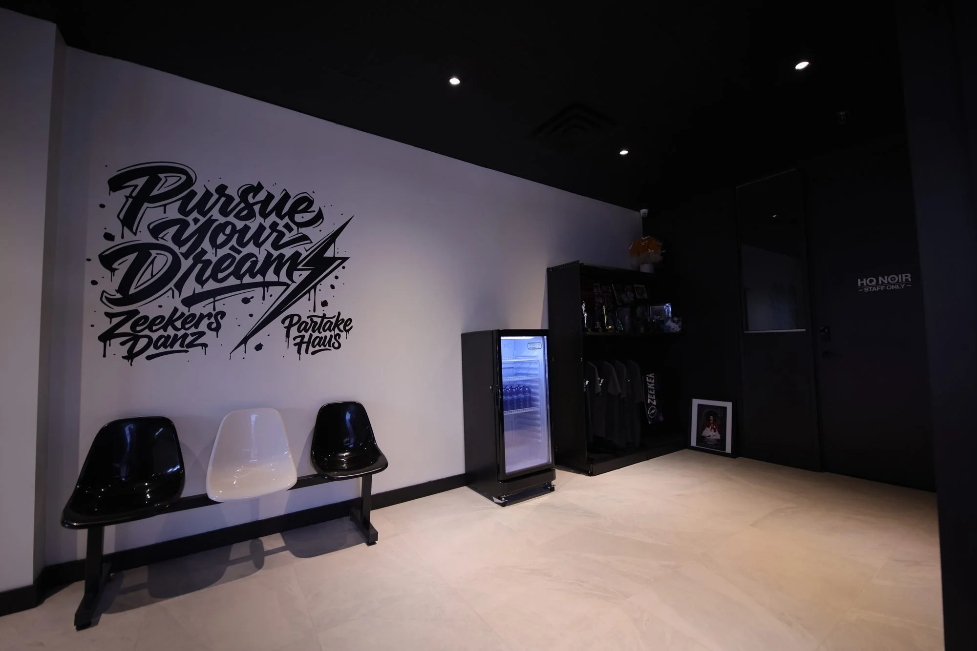 The studio reception: a black mural that reads Pursue Your Dream over a row of black and white chairs.