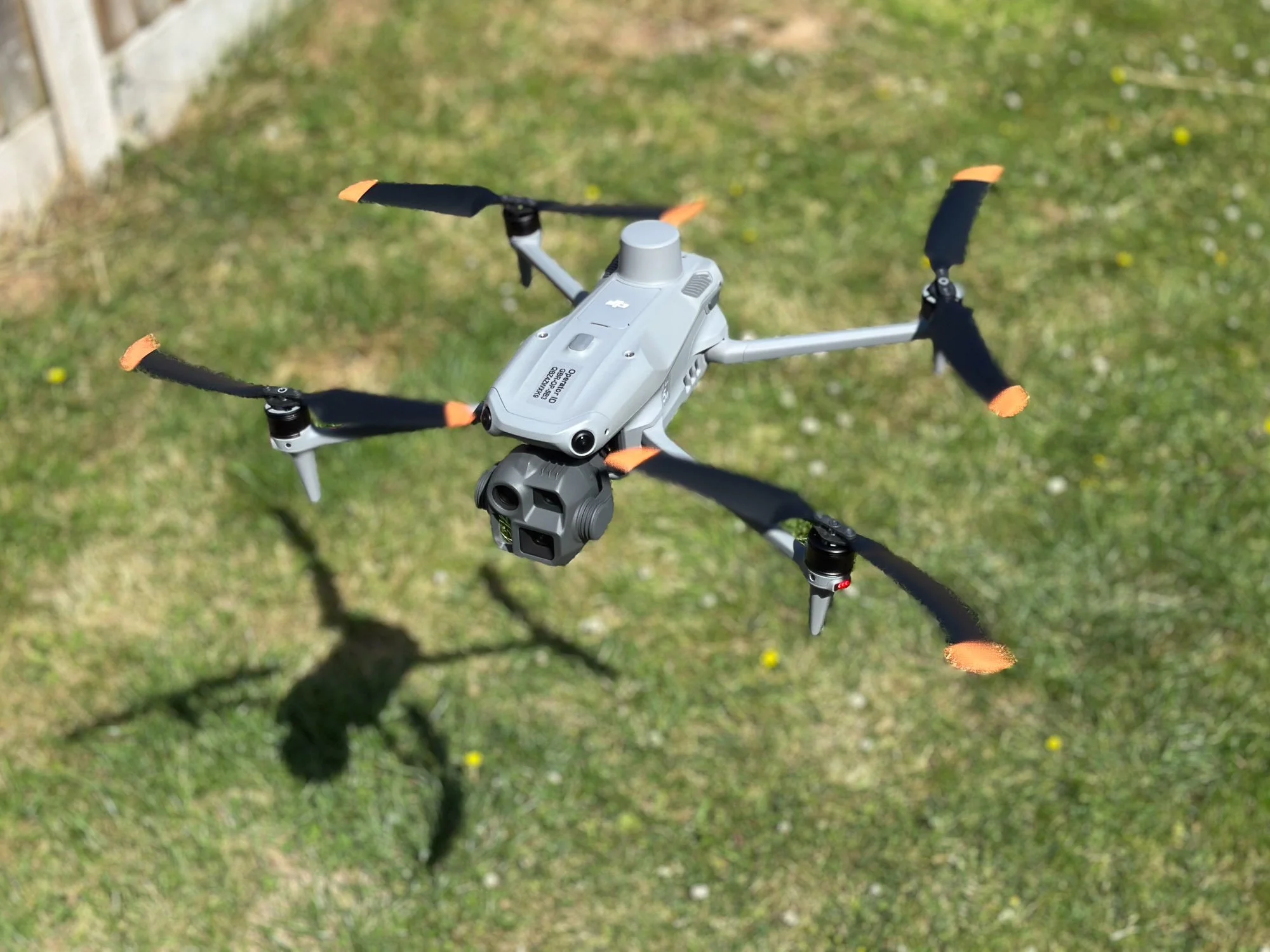 DJI Matrice 4E hovering with spinning propellers and shadow underneath