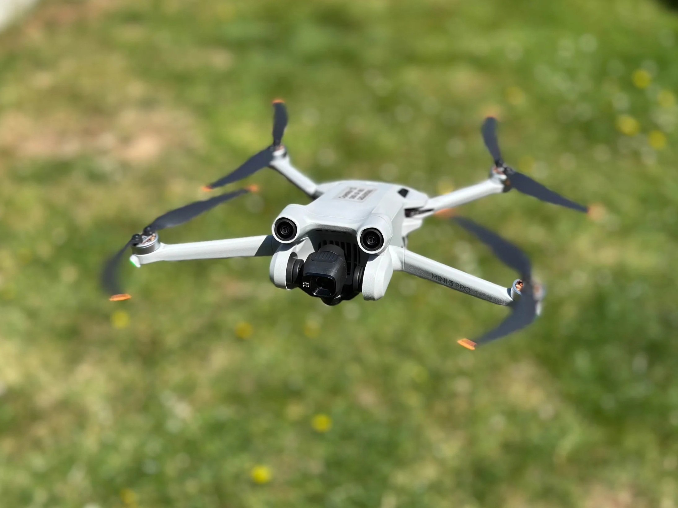 DJI Mini 3 Pro hovering above green grass