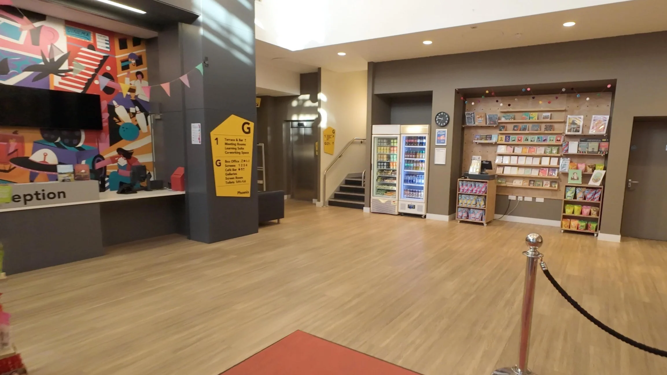FPV drone shot flying towards the entrance of a theatre venue, capturing architectural details, signage, and welcoming lighting.