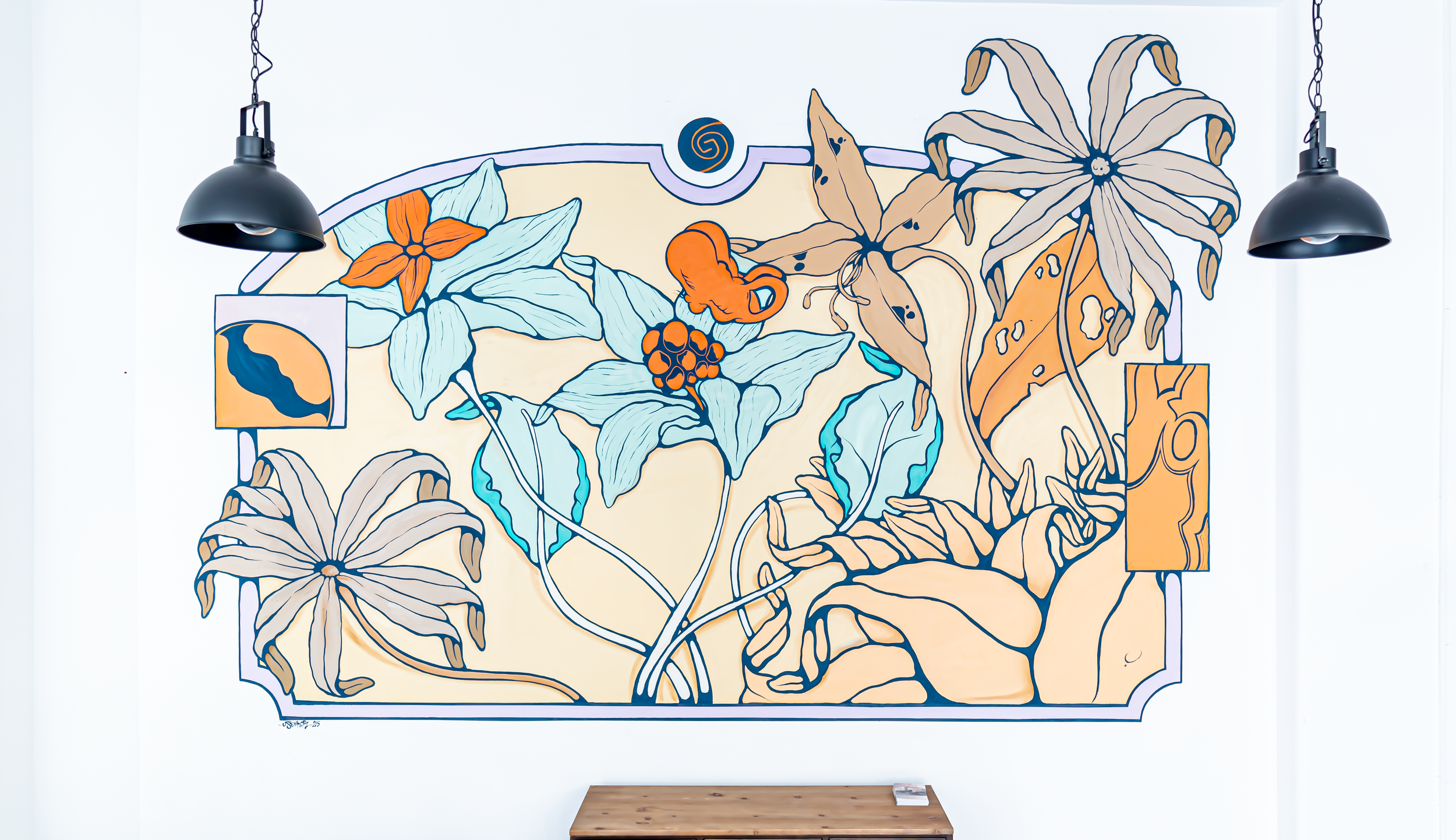 Mural de arte com desenhos de flores e folhas em cores azul, laranja, bege e preto, iluminado por dois refletores pretos suspensos.