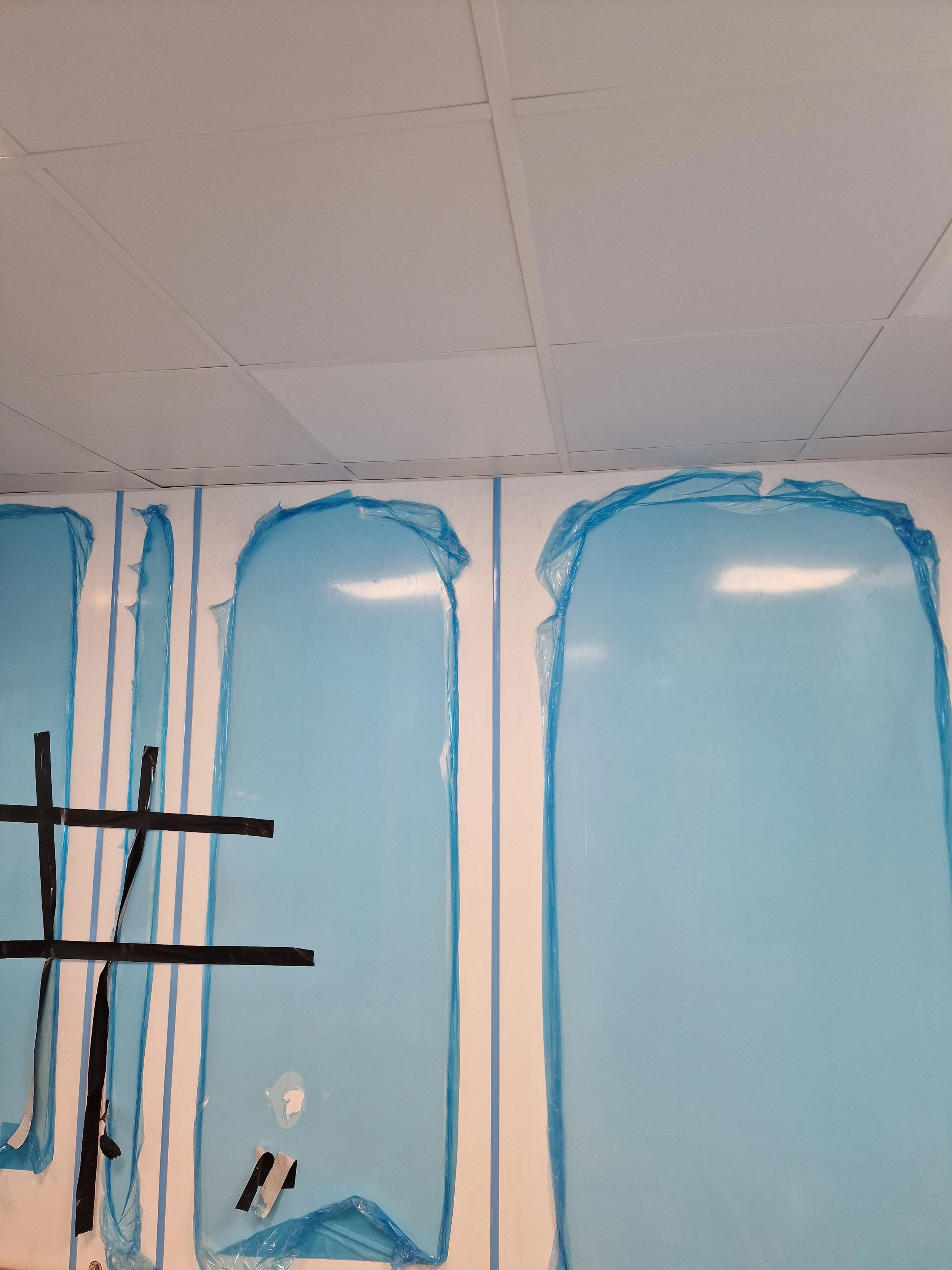 Room with blue plastic covering parts of the wall and black tape, possibly under construction or renovation.