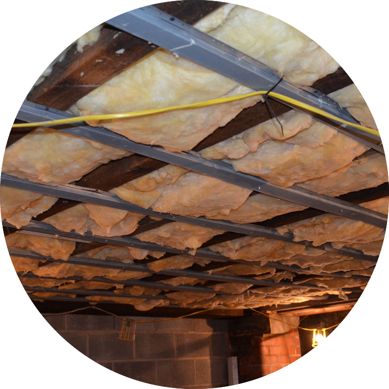 Insulation installed between ceiling joists in an unfinished basement or attic.