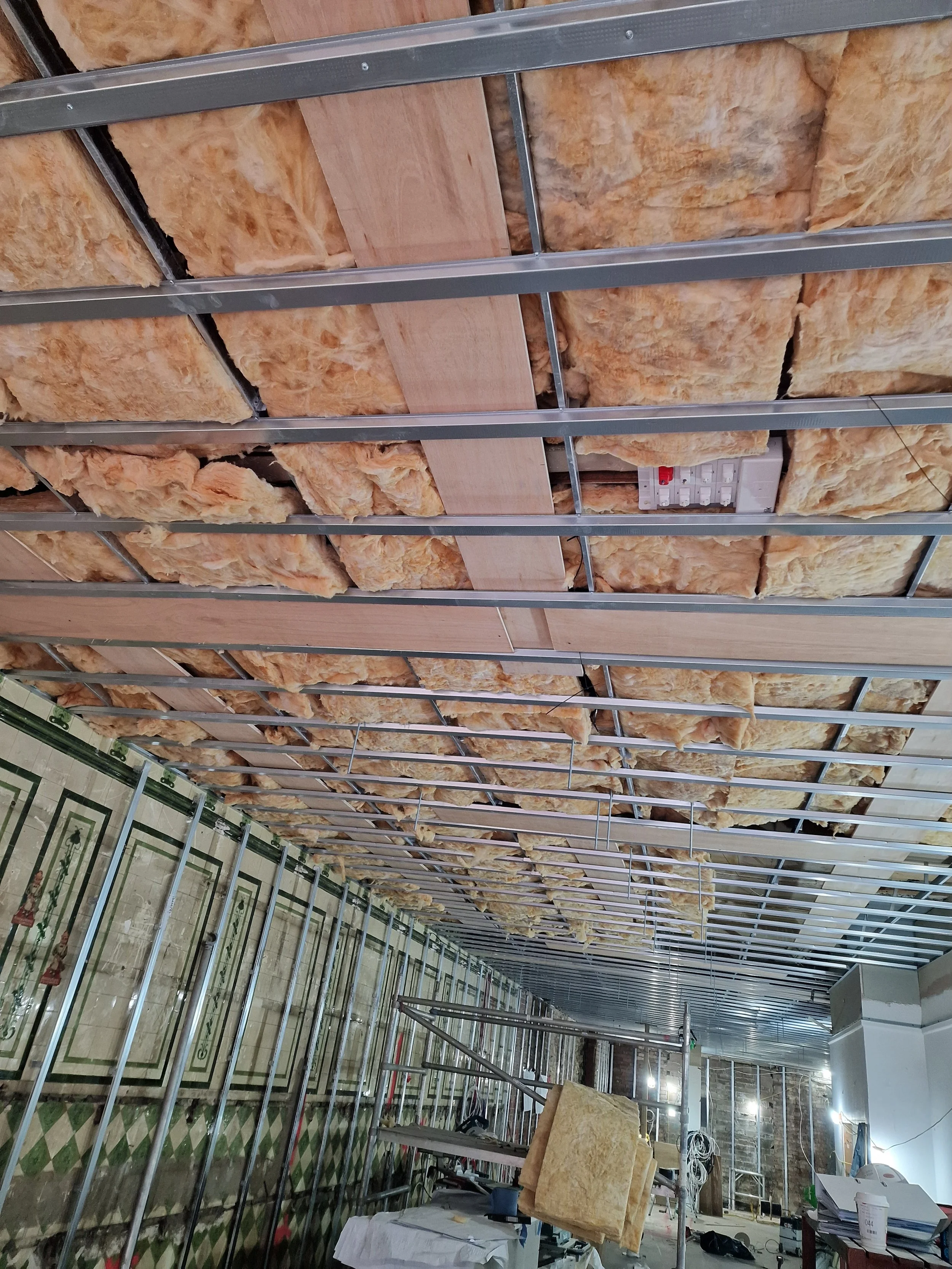 Ceiling under construction with insulation and metal framework in a building.