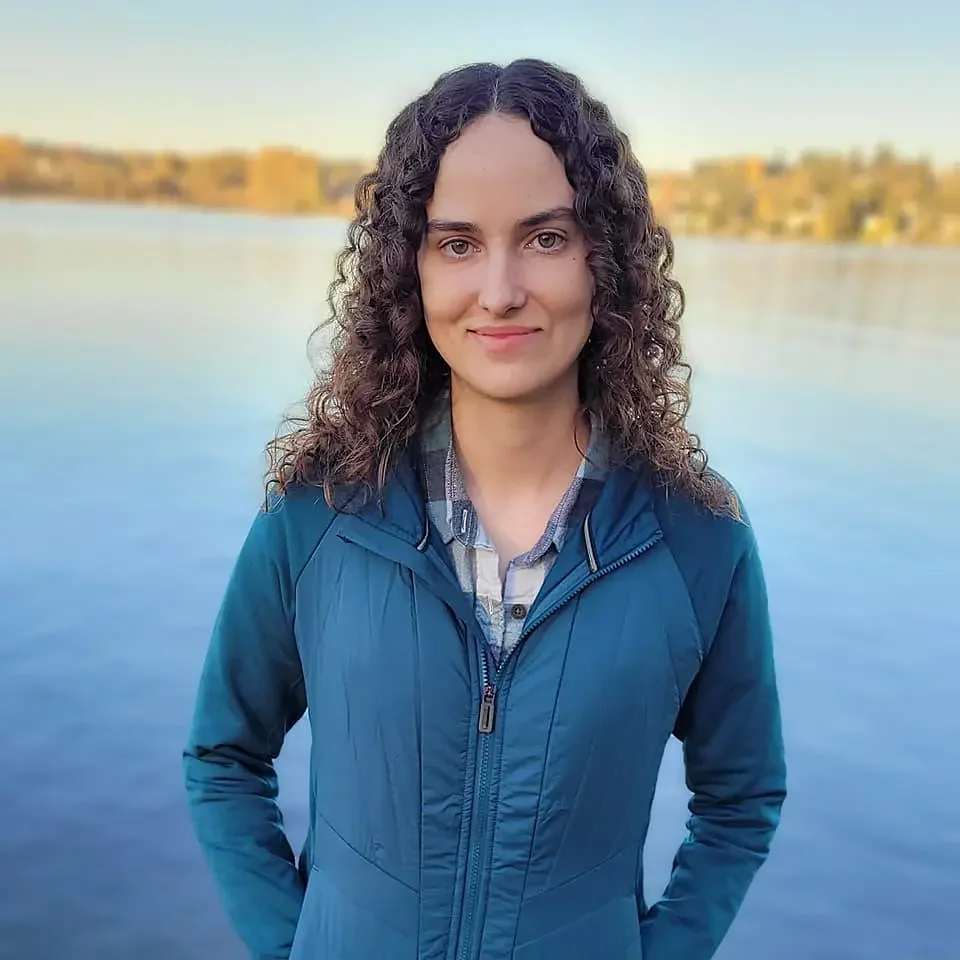 Licensed Therapist, Reagan Hylton, standing by a lake during sunset. Offering therapy services in CO & TX.