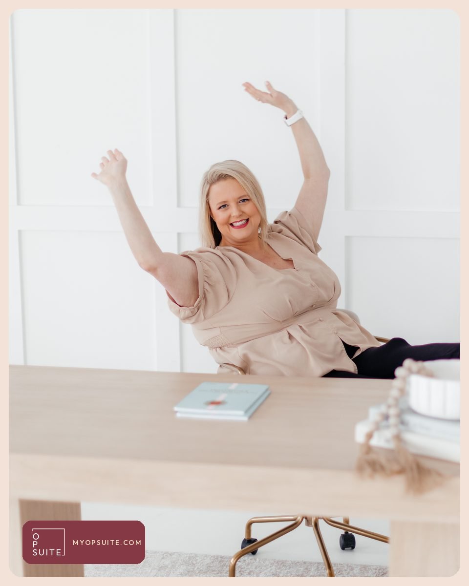 Samantha Cox celebrating at her desk with both arms raised after finishing her annual business plan