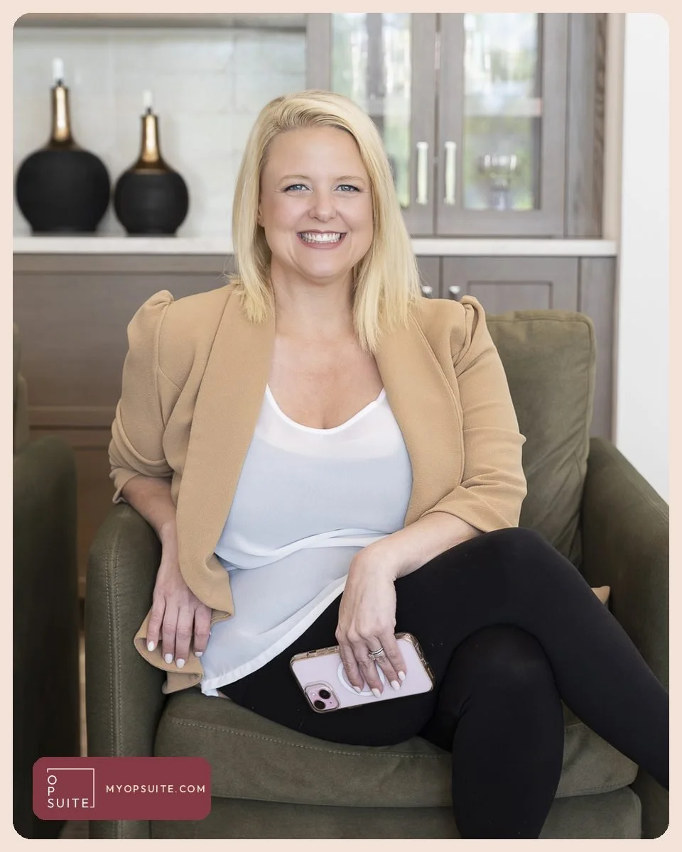 Samantha Cox of OpSuite in a tan blazer, seated in an armchair and smiling, holding her phone.