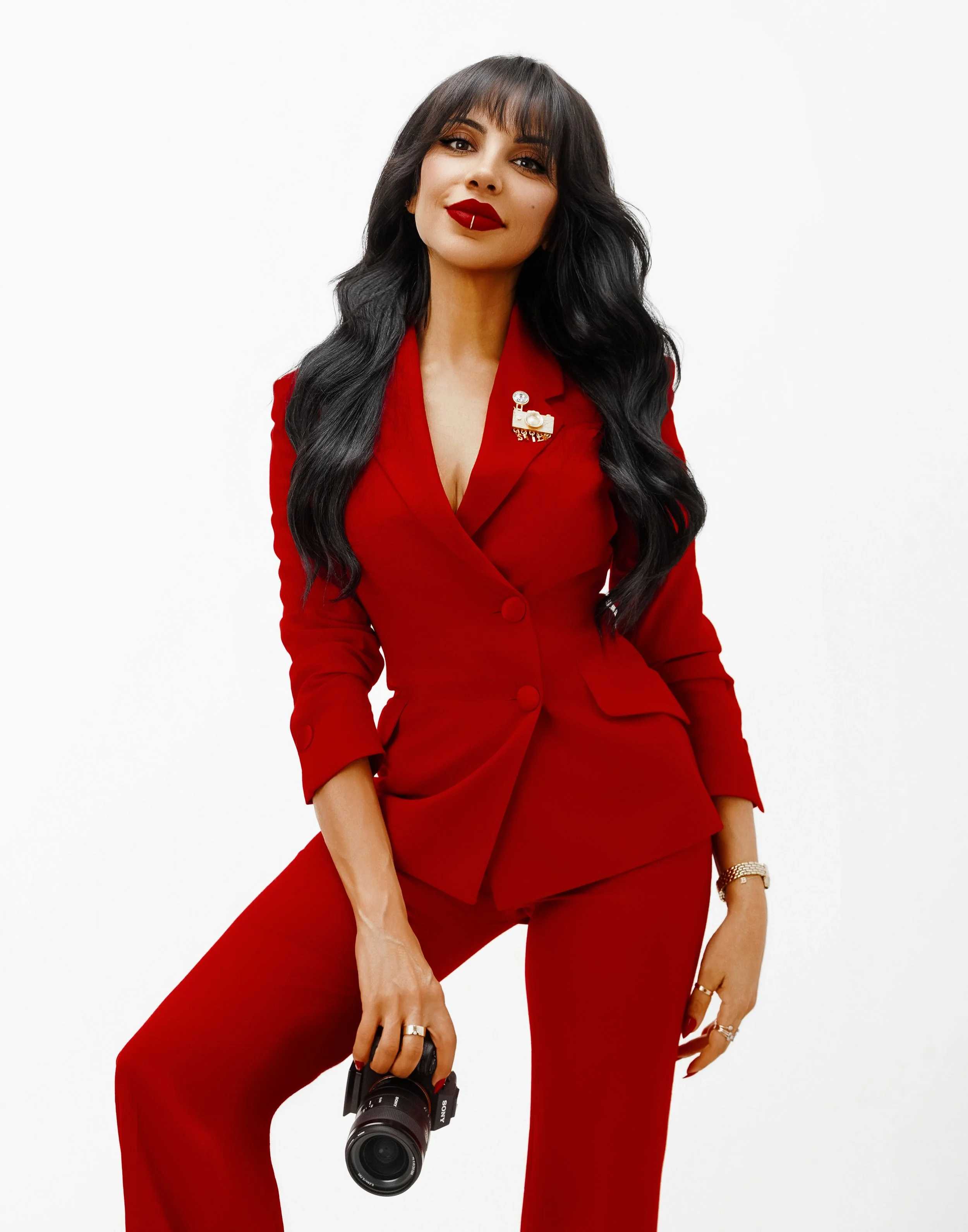 Esther Kay in a red pant suit looking at the camera.
