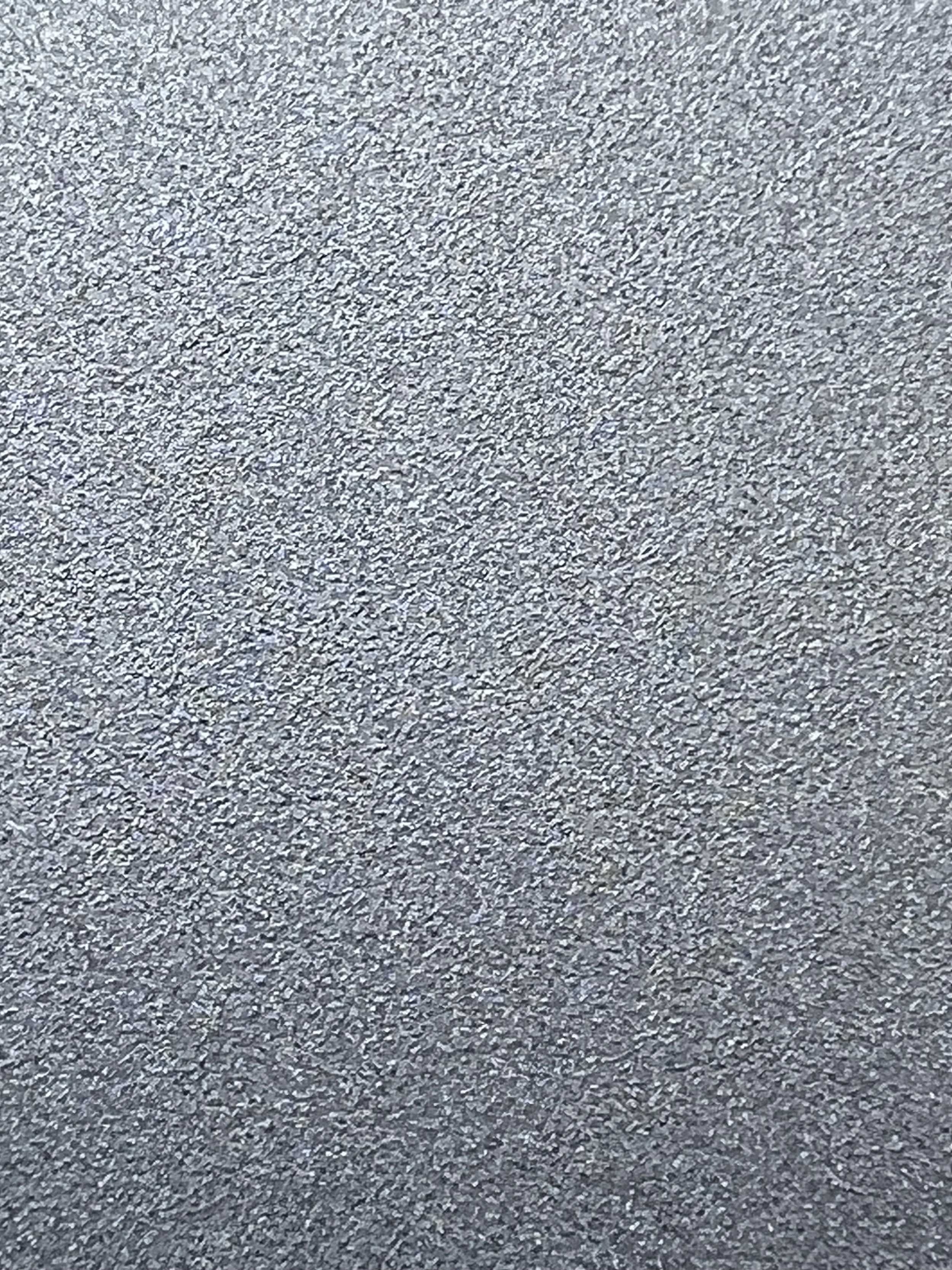 Close-up image of a textured gray surface, resembling a metallic or concrete material.