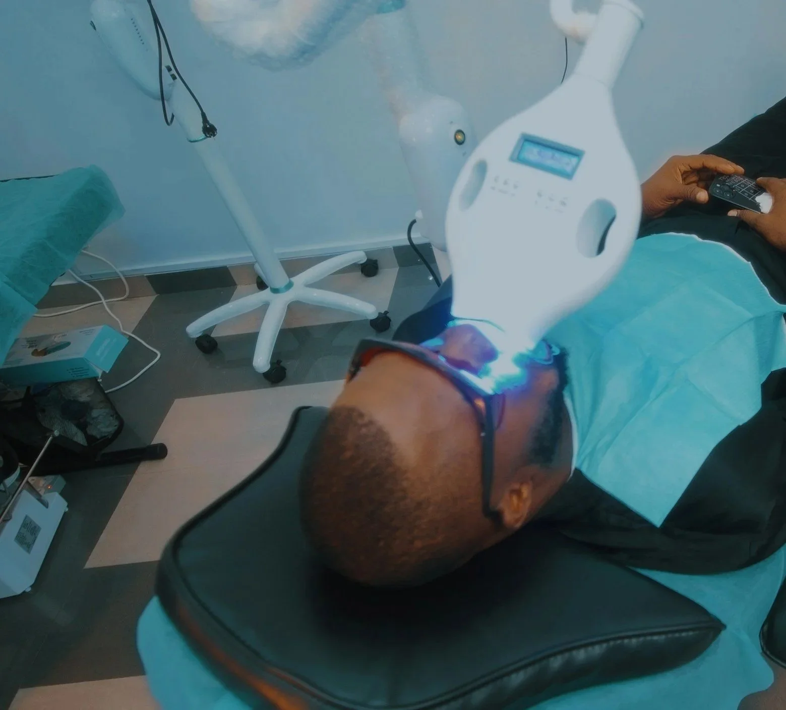 Un medico sta eseguendo un trattamento di terapia con luce laser sul collo di un paziente disteso su un lettino, in una stanza medica.