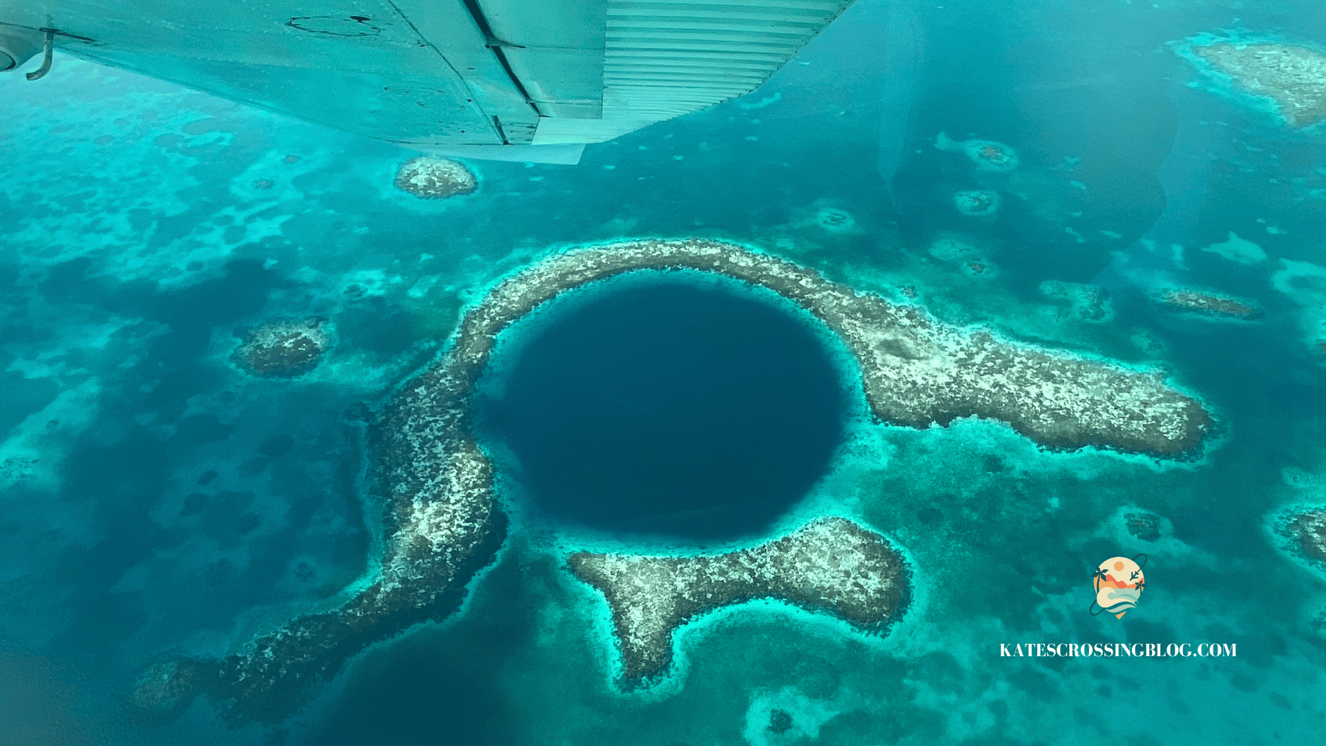 Arial view of Belize's Great Blue Hole with a dark blue center and bright turquoise water and coral surrounding the hole in the middle of the ocean. 