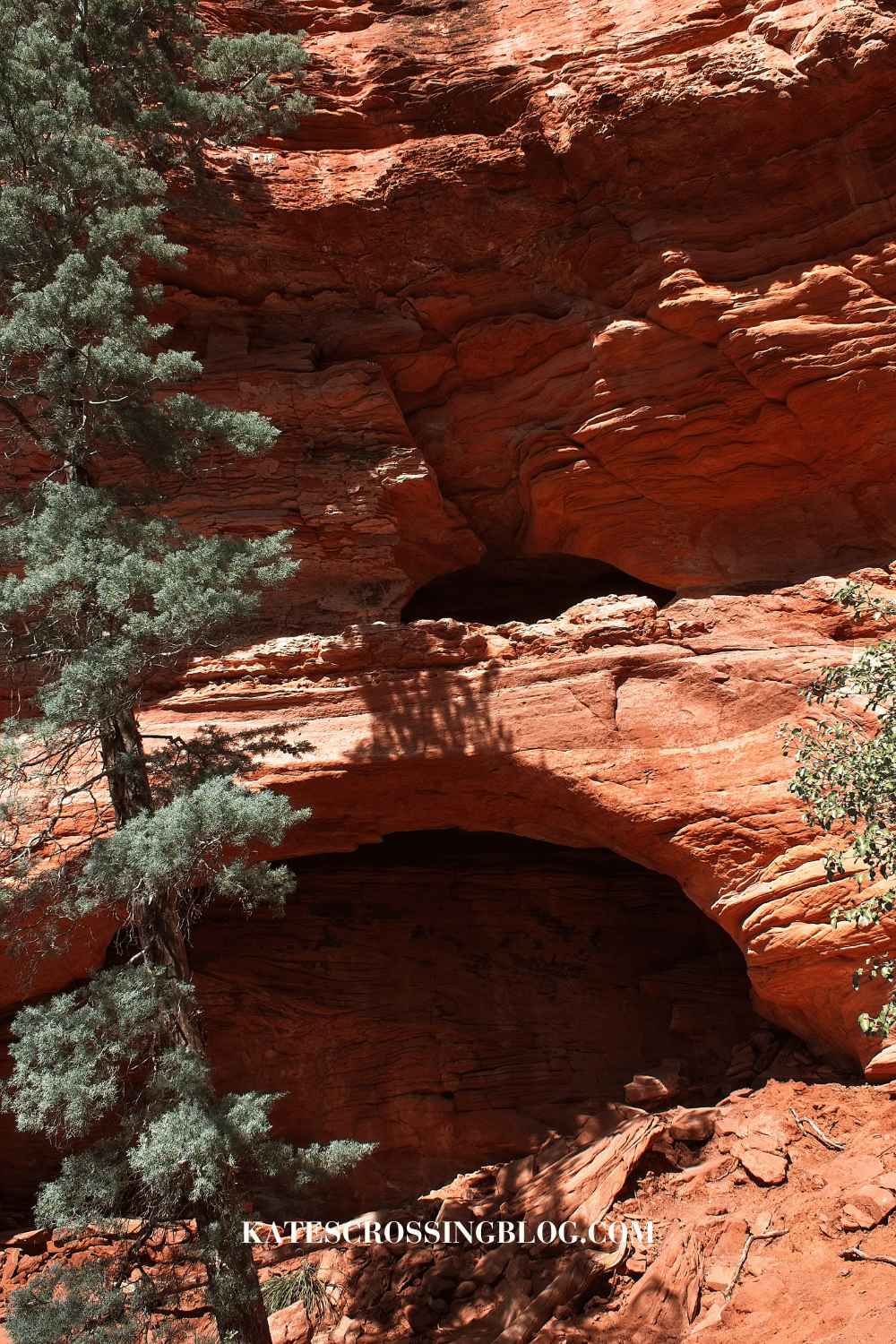 Outside entrance to the hidden Soldier Pass Cave in Sedona, nestled within the striking red rock formations and surrounded by pine trees.