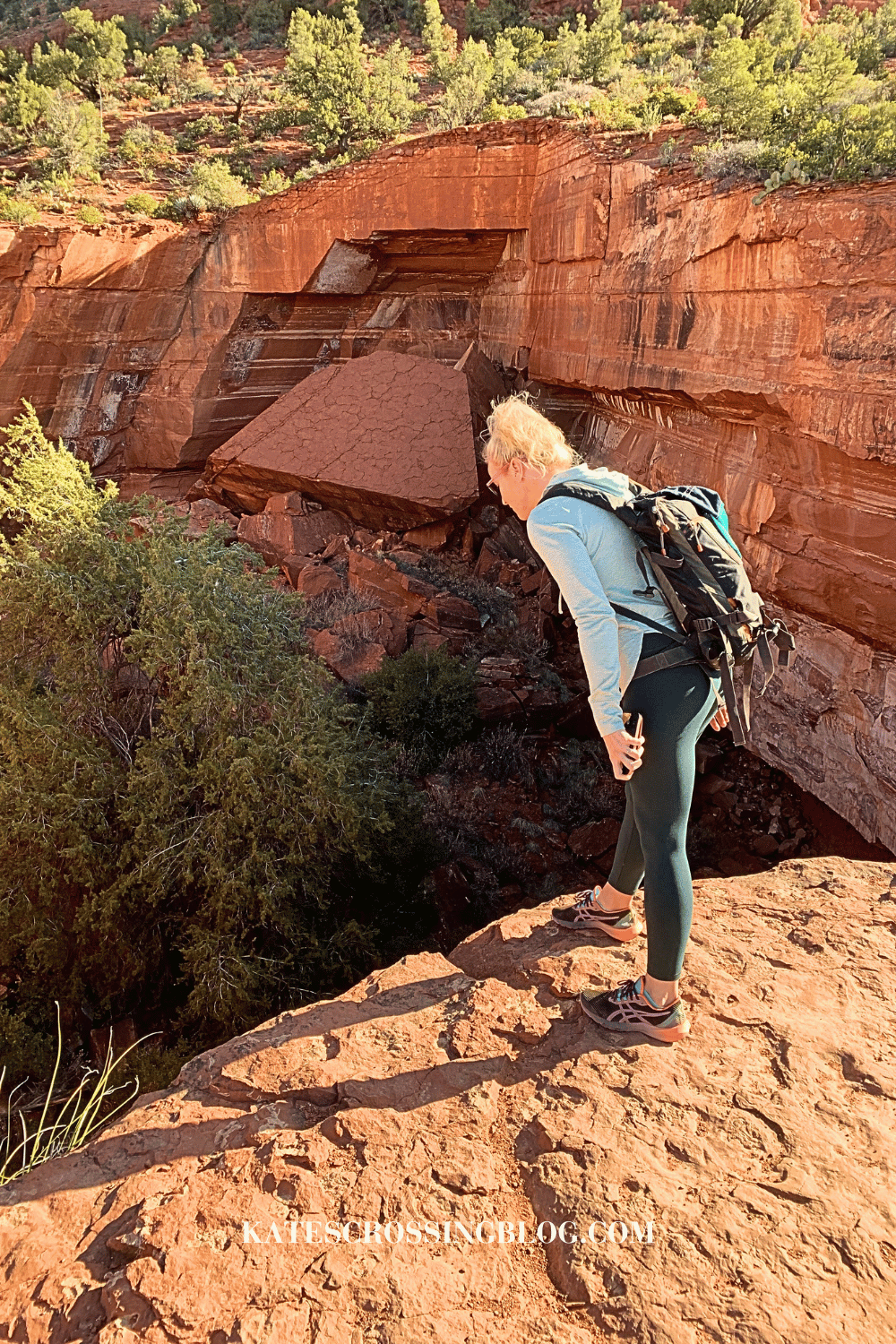 Kate standing at the edge of Devil's Kitchen sinkhole on the Soldier Pass Trail in Sedona, looking down into the massive hole.