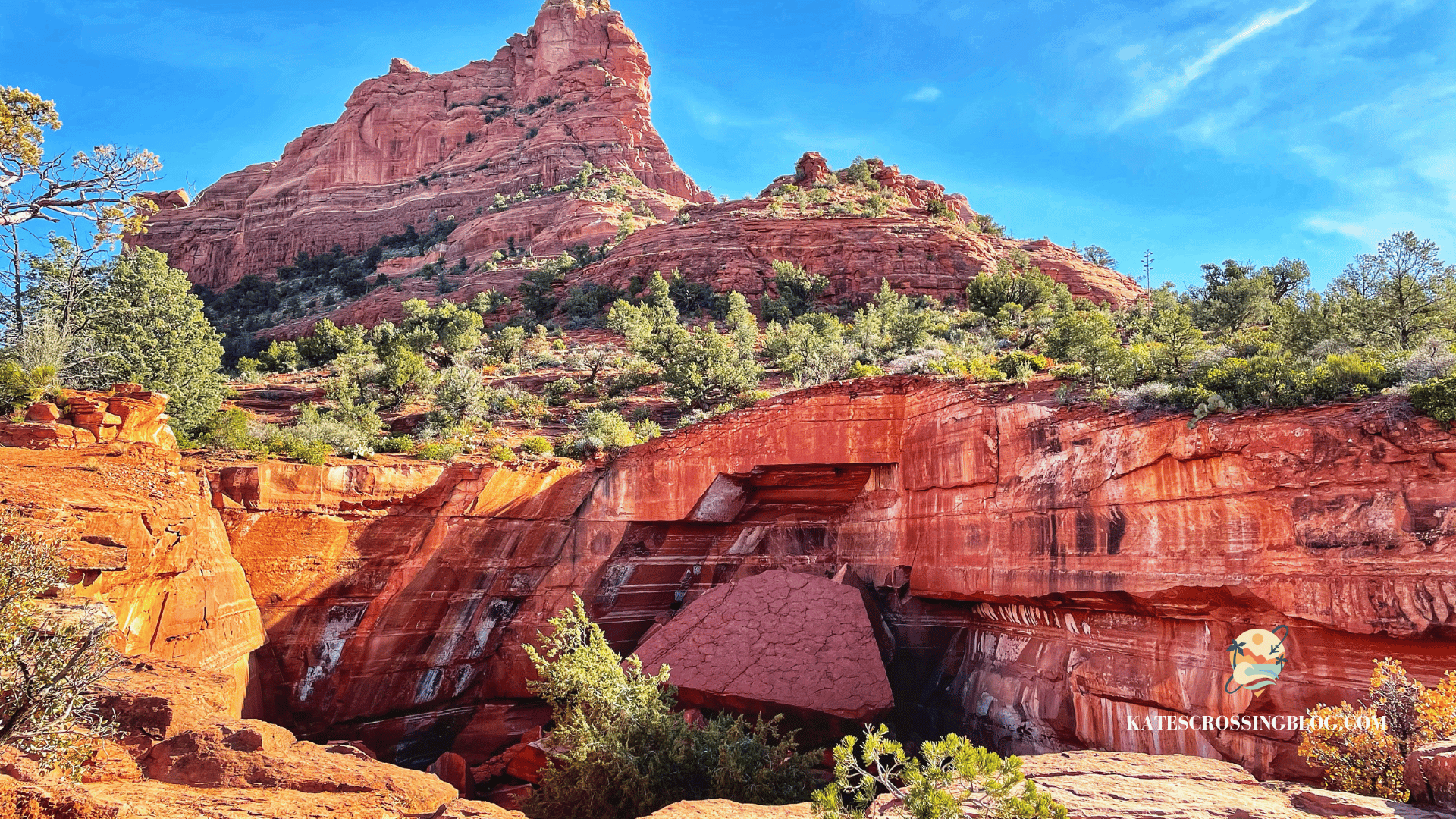 Devil's Kitchen sinkhole on the Soldier Pass Trail in Sedona, framed by vibrant red rock formations and lush greenery under a bright blue sky.