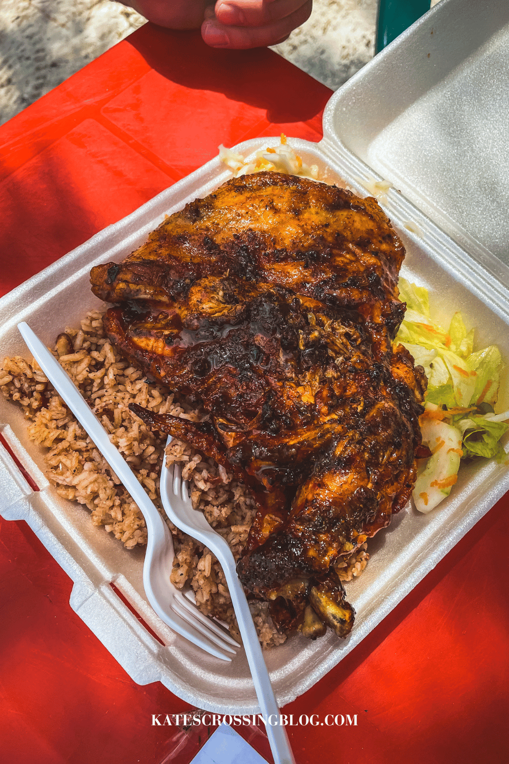 Jerk BBQ chicken with Rice and Beans in a to-go container. 