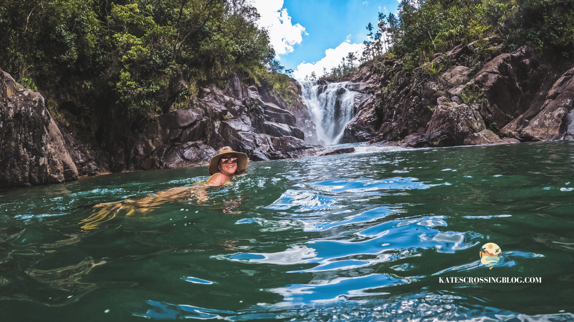 Kate swimming in the green pool below Big Fock Falls waterfall wearing a sunhat. 