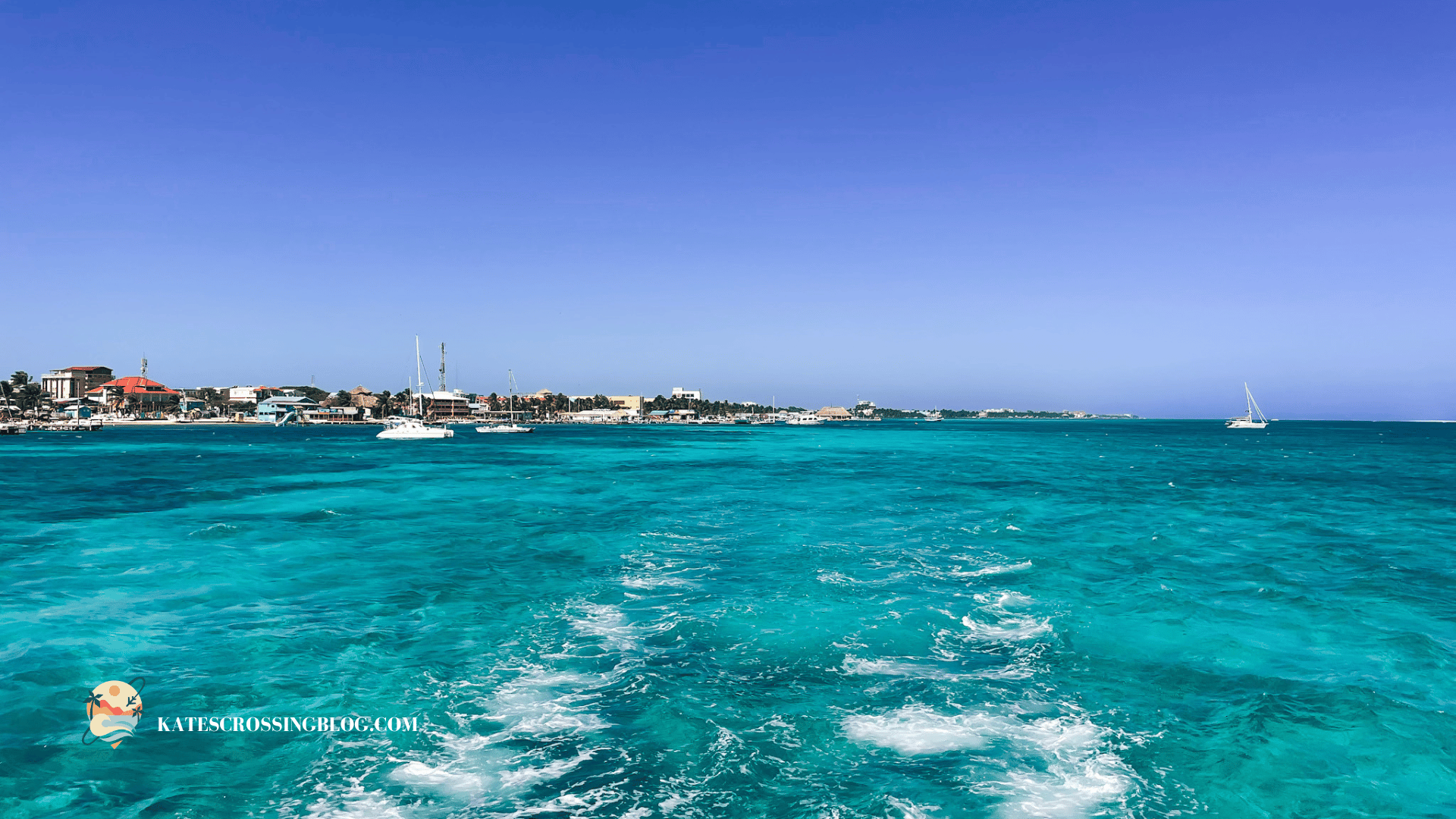 View of Belize's coastline from a water taxi, showcasing the vibrant blue waters and sailboats, capturing the essence of island hopping in Belize.
