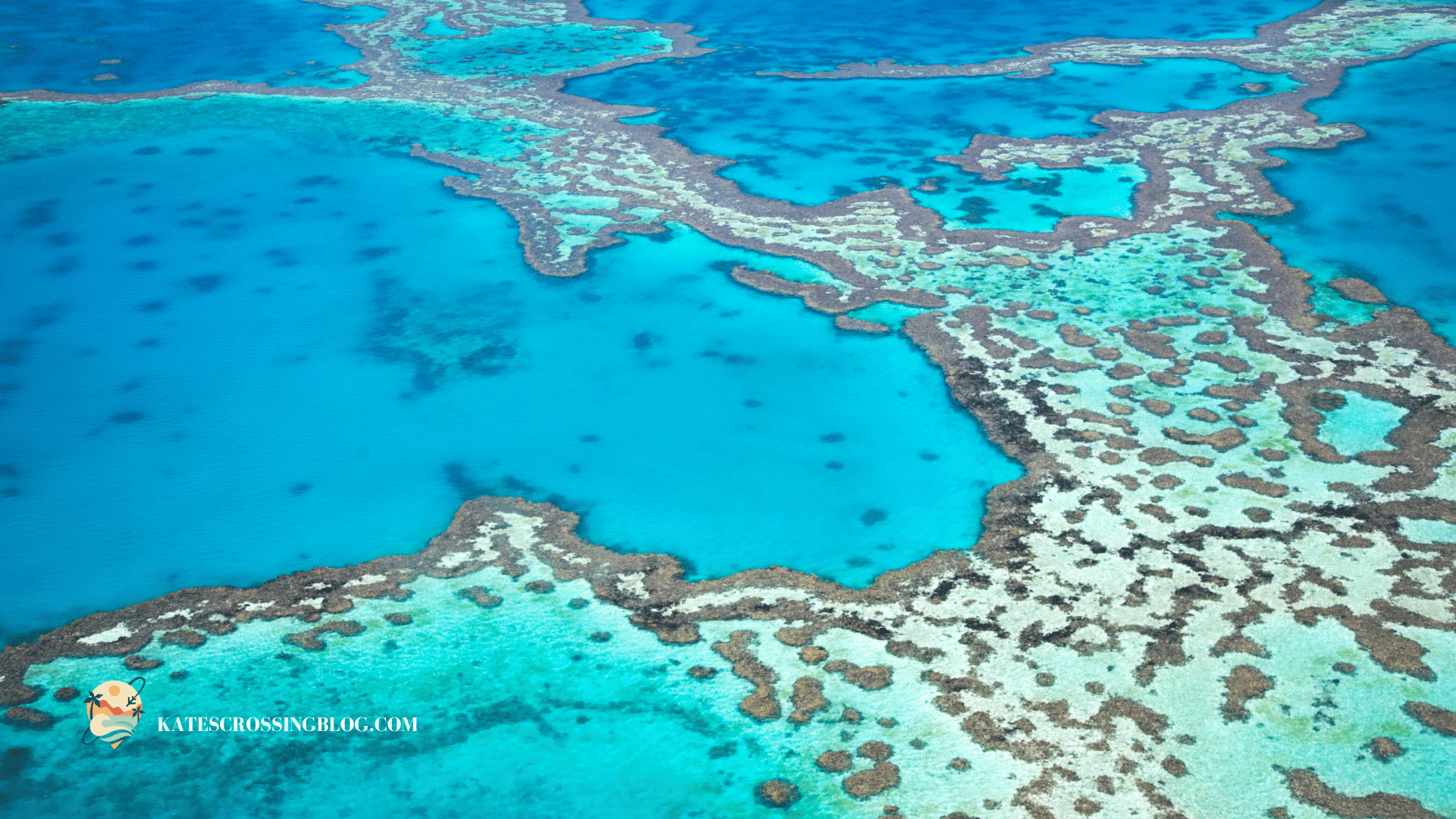 Aerial view of the Belize Barre Reef with turquoise and blue waters changing colors and dark spots where the reef is close to the surface. 