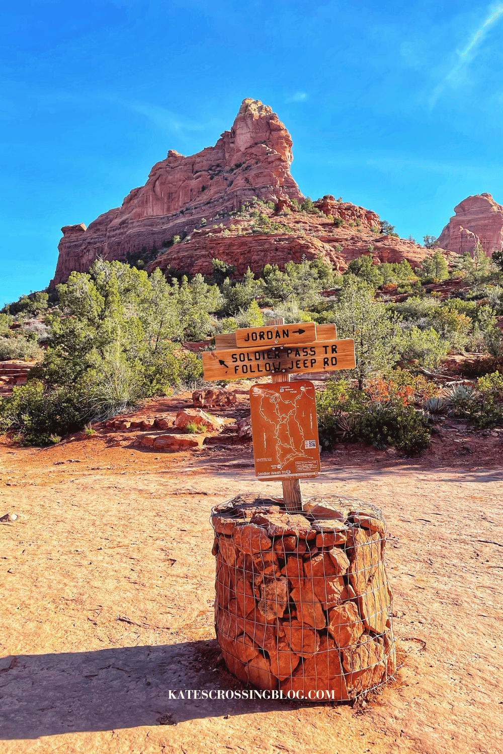 Trail sign for Soldier Pass Trail and Jordan Trail at the trailhead, set against the backdrop of Sedona's iconic red rock formations and a clear blue sky.