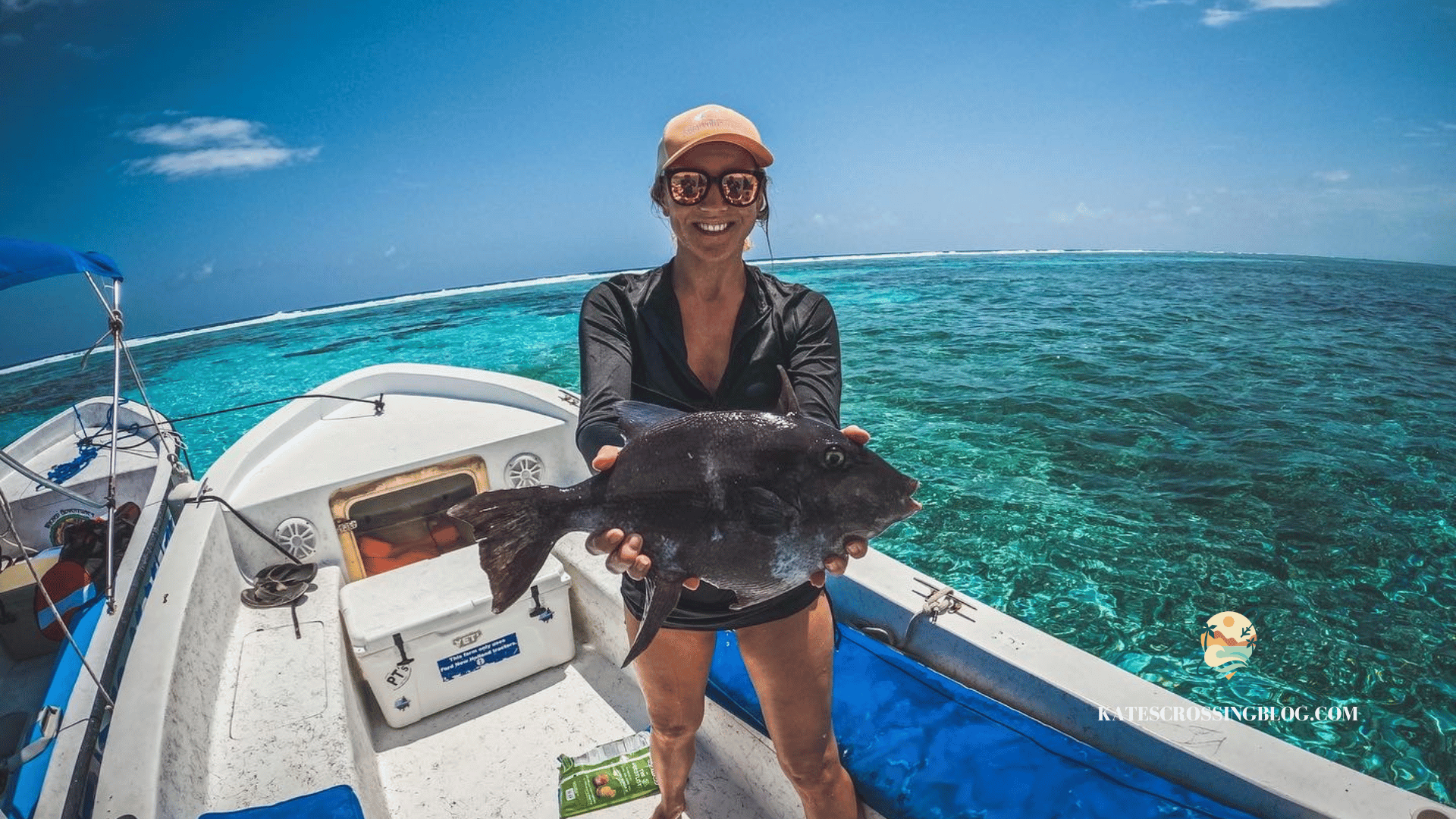 Kate holding up a large grey fish while standing on a boat out on the turquoise waters of Belize.