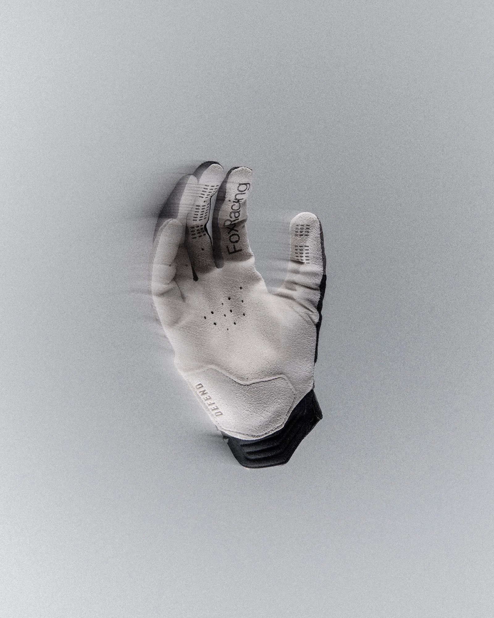 A white Fox Racing mountain biking glove with black grip detailing and a black wrist cuff, photographed against a minimalist light grey background. The glove is positioned palm-up with the fingers slightly spread, showing textured grip panels, ventil