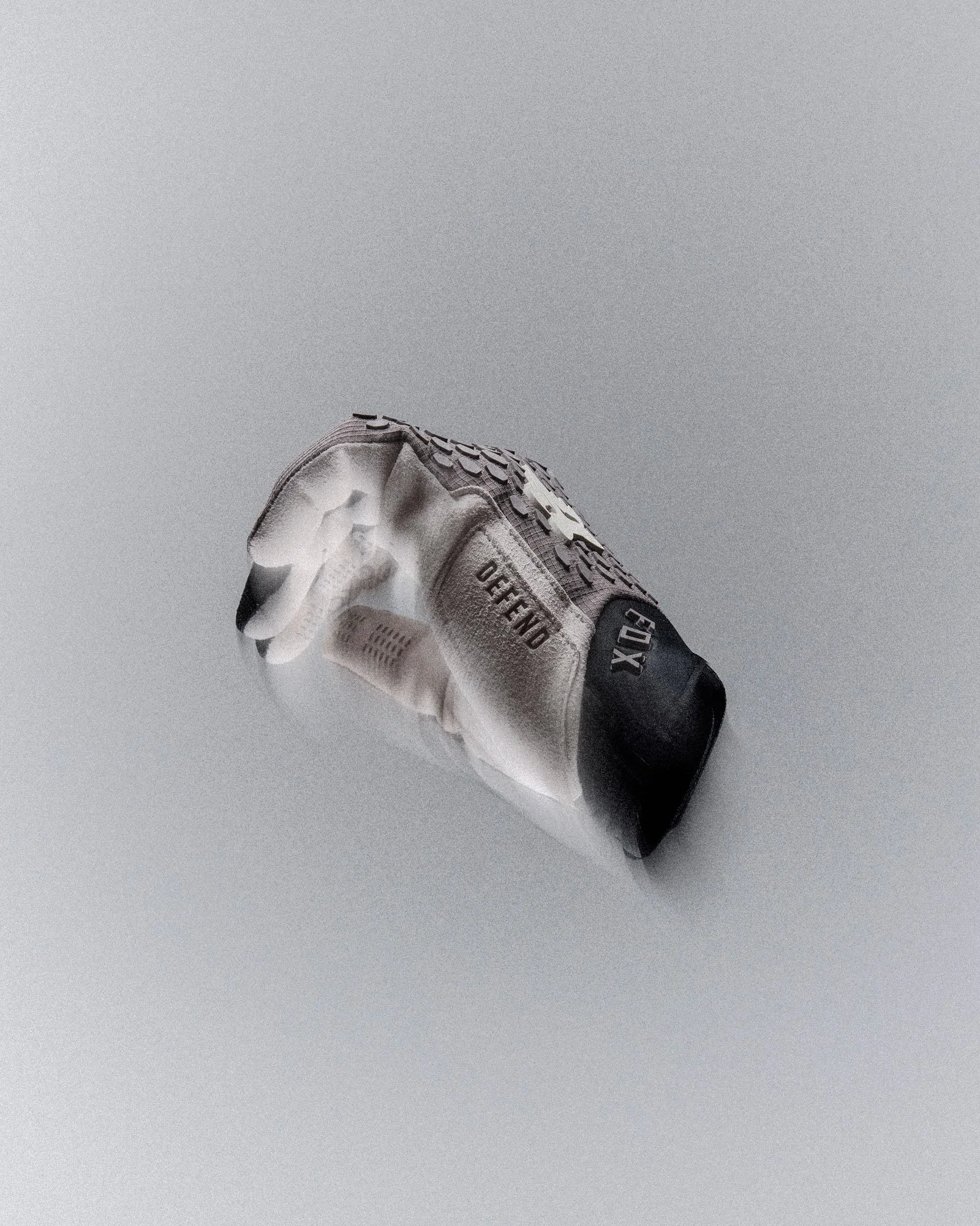 A white Fox Racing mountain biking glove with black grip detailing and a black wrist cuff, photographed against a minimalist light grey background. The glove is positioned palm-up with the fingers slightly spread, showing textured grip panels, ventil