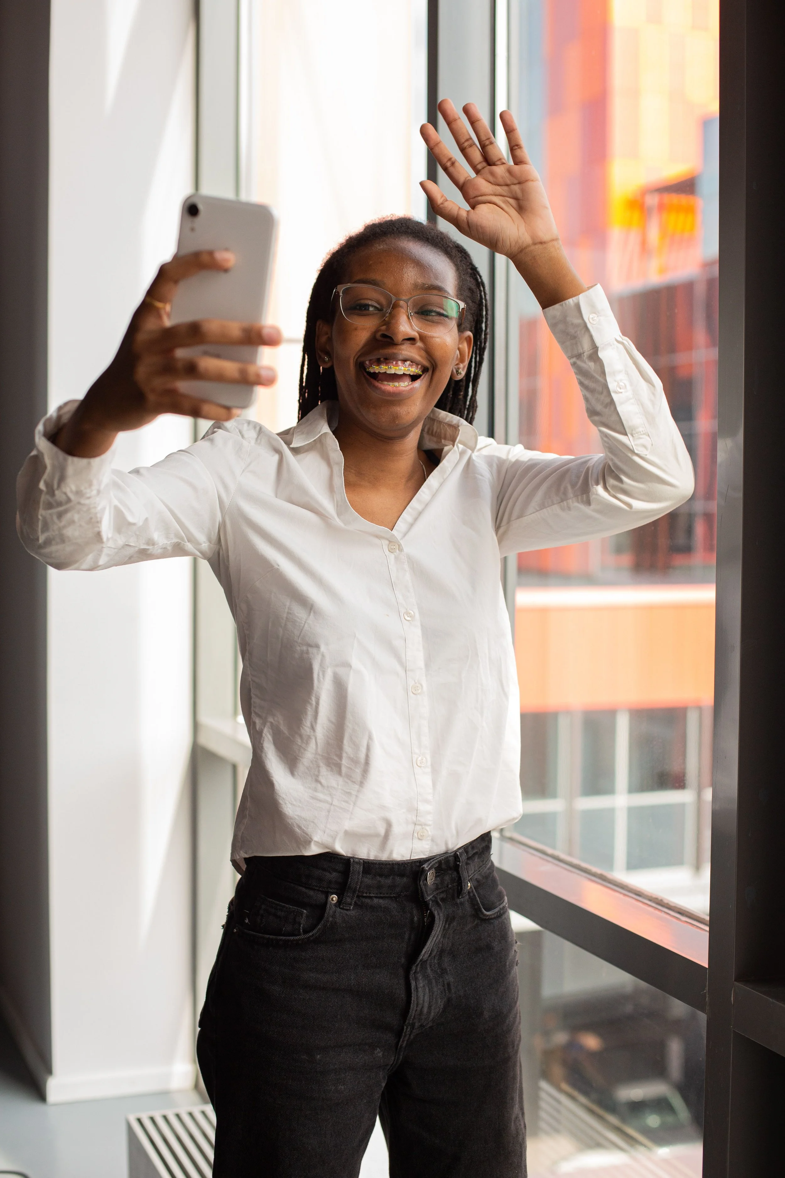 Women in business casual clothes taking a selfie by an office window