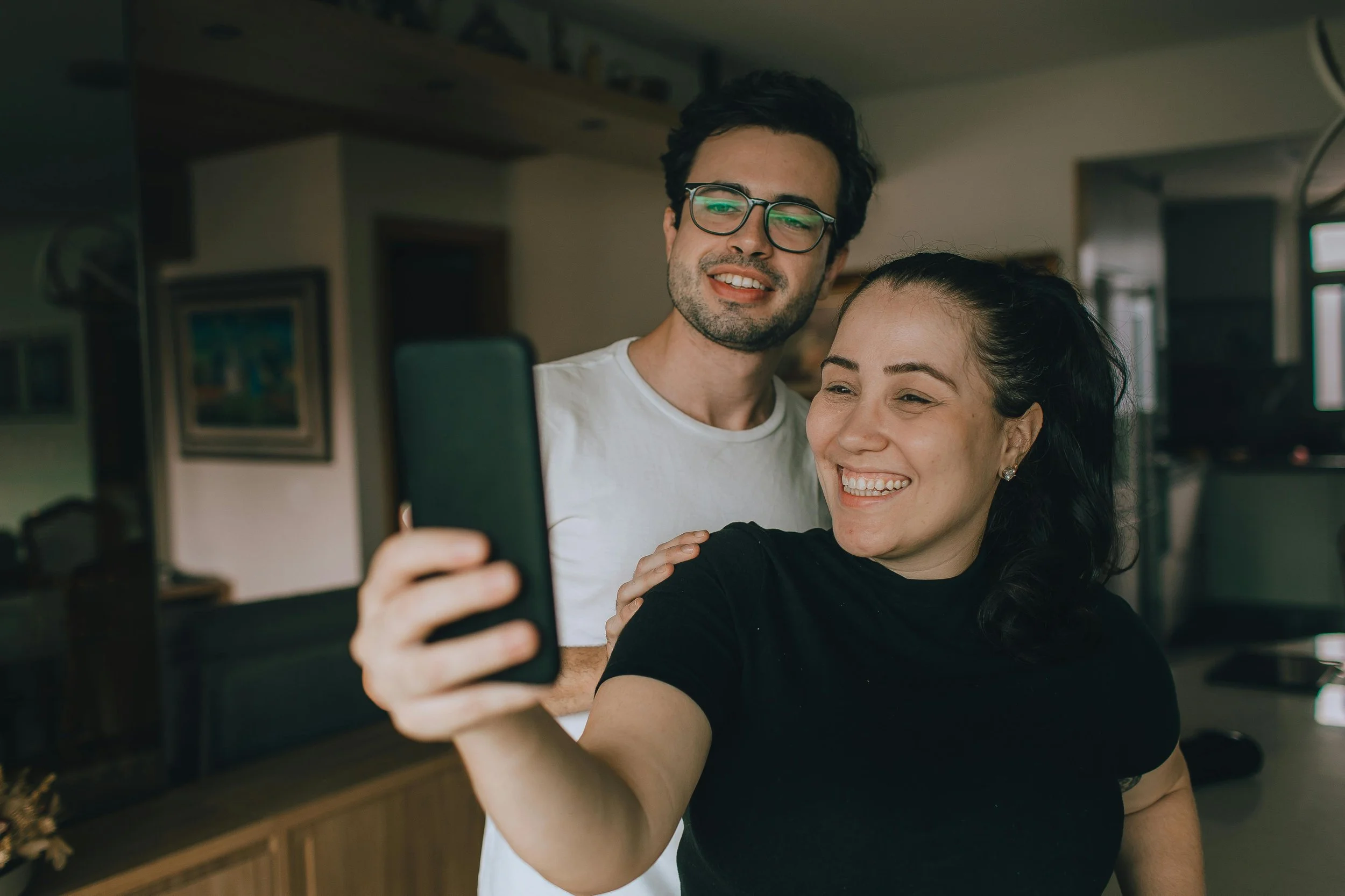 Woman holding phone outward to take a selfie with a man. They are both smiling