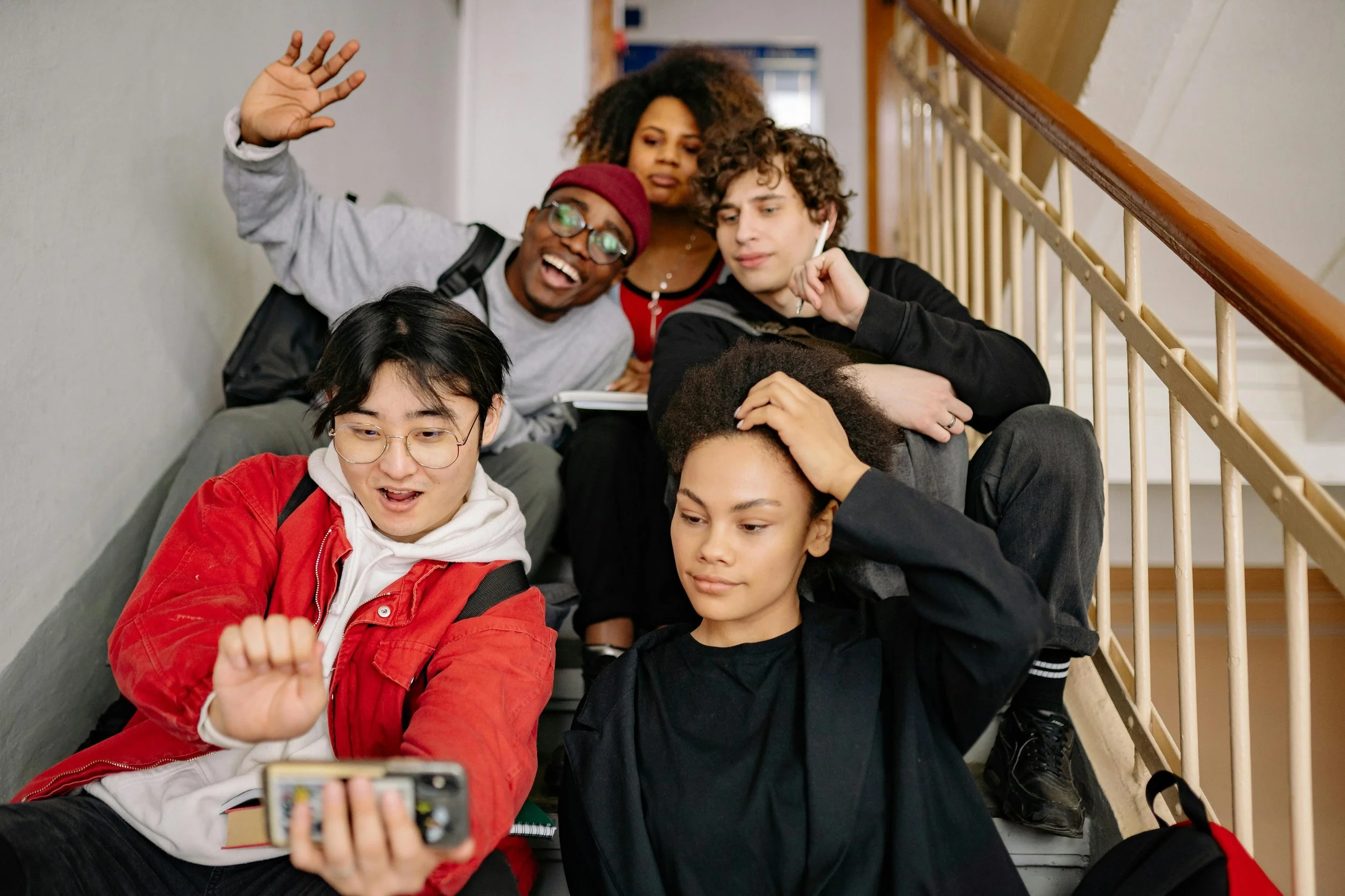 Group of 5 college students taking a selfie while sitting on some stairs