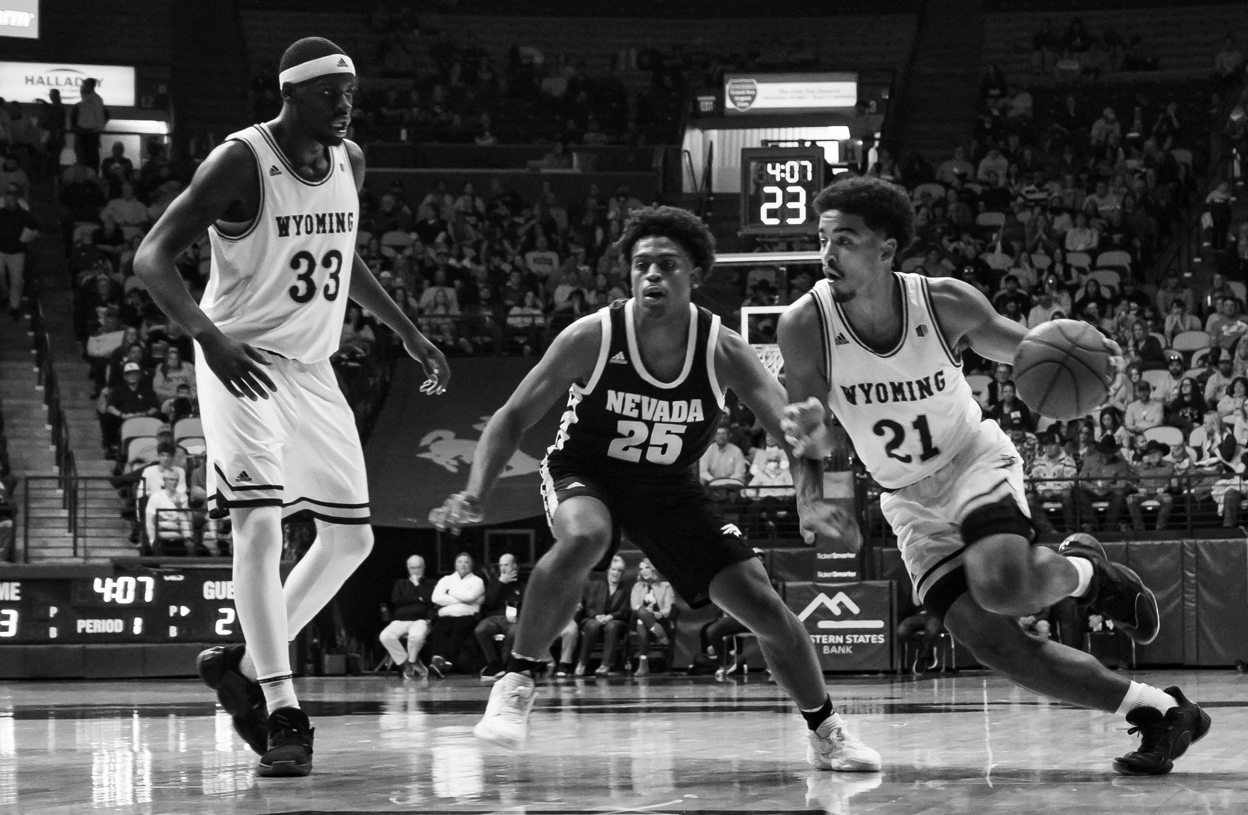 Wyoming freshman guard Noah Reynolds (21) dribbles around Nevada Wolfpack player Grant Sherfield (25).  Graham Ike gets ready to set a screen against Sherfield, allowing Reynolds to get to the basket. Wyoming would beat the Wolfpack 74-61 on Feb.  26