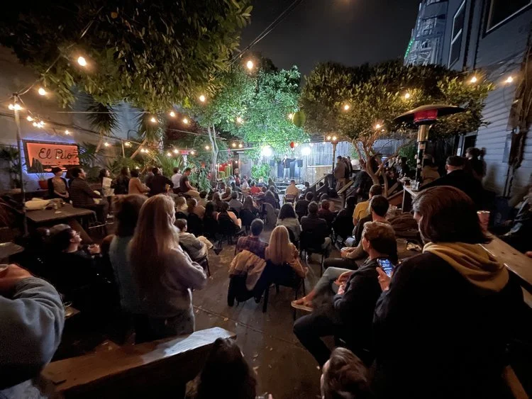 Crowded bar space with tons of indoor plants hanging from the ceiling.